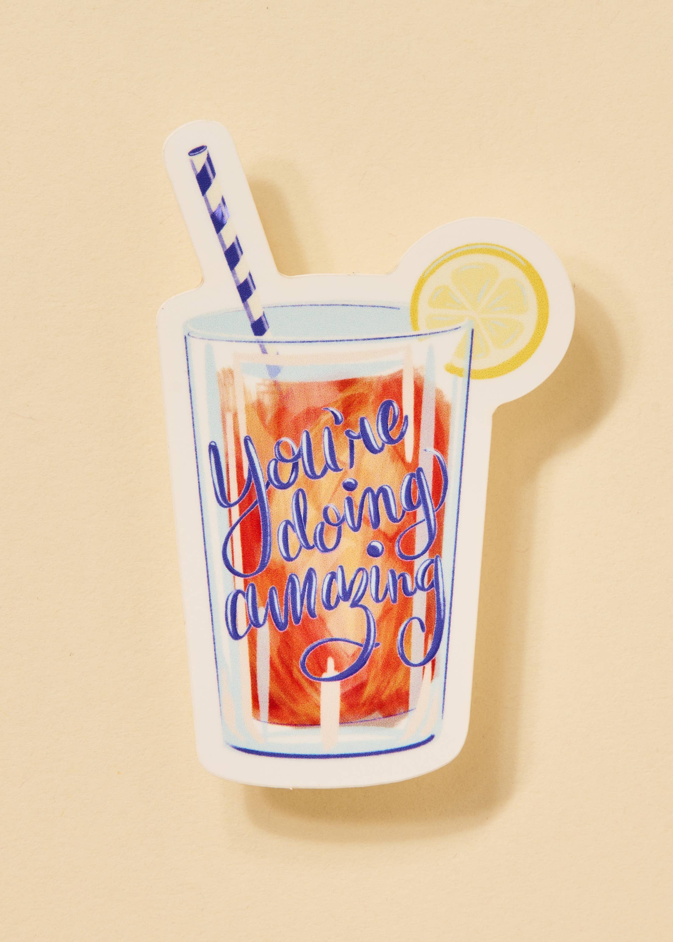 Glass with colorful drink, straw, and lemon slice on a beige background