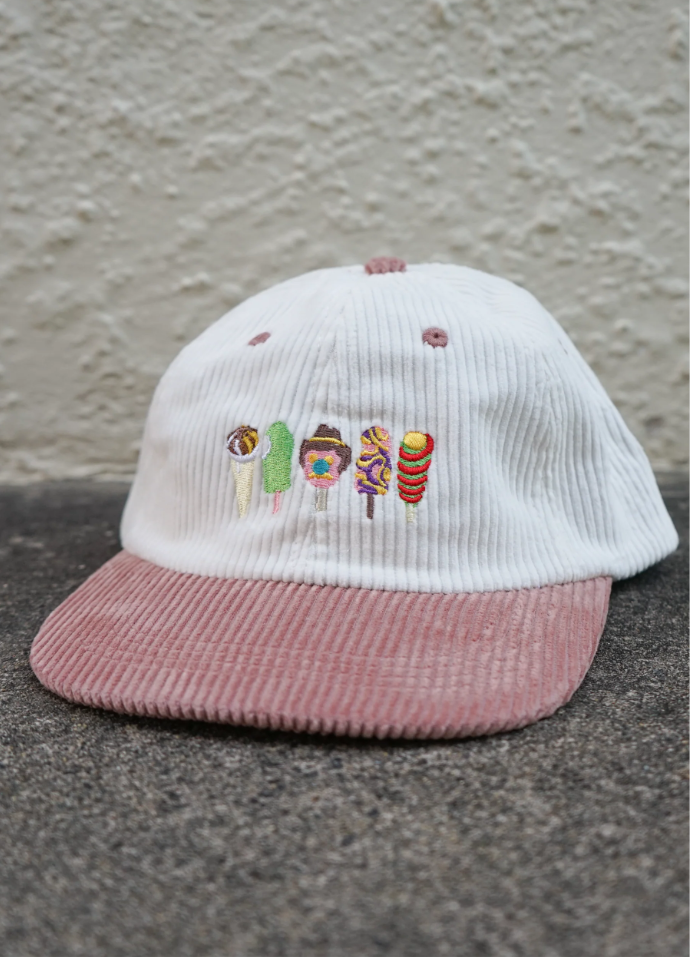White and pink cap with embroidered designs on a textured surface