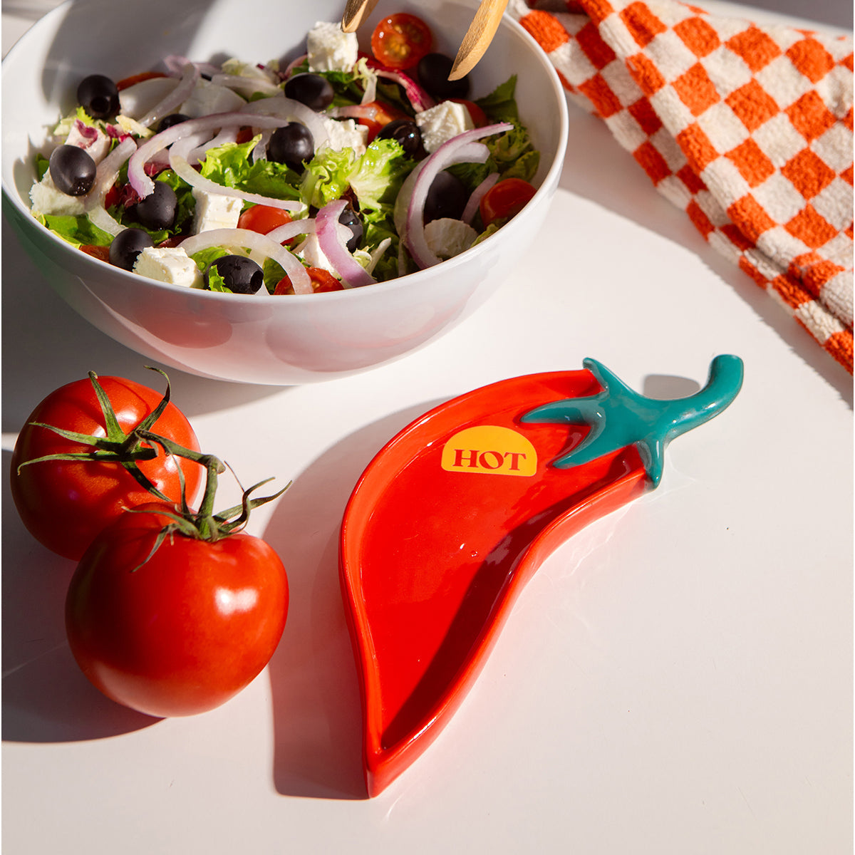 Red chilli ceramic spoon rest holding wooden spoon