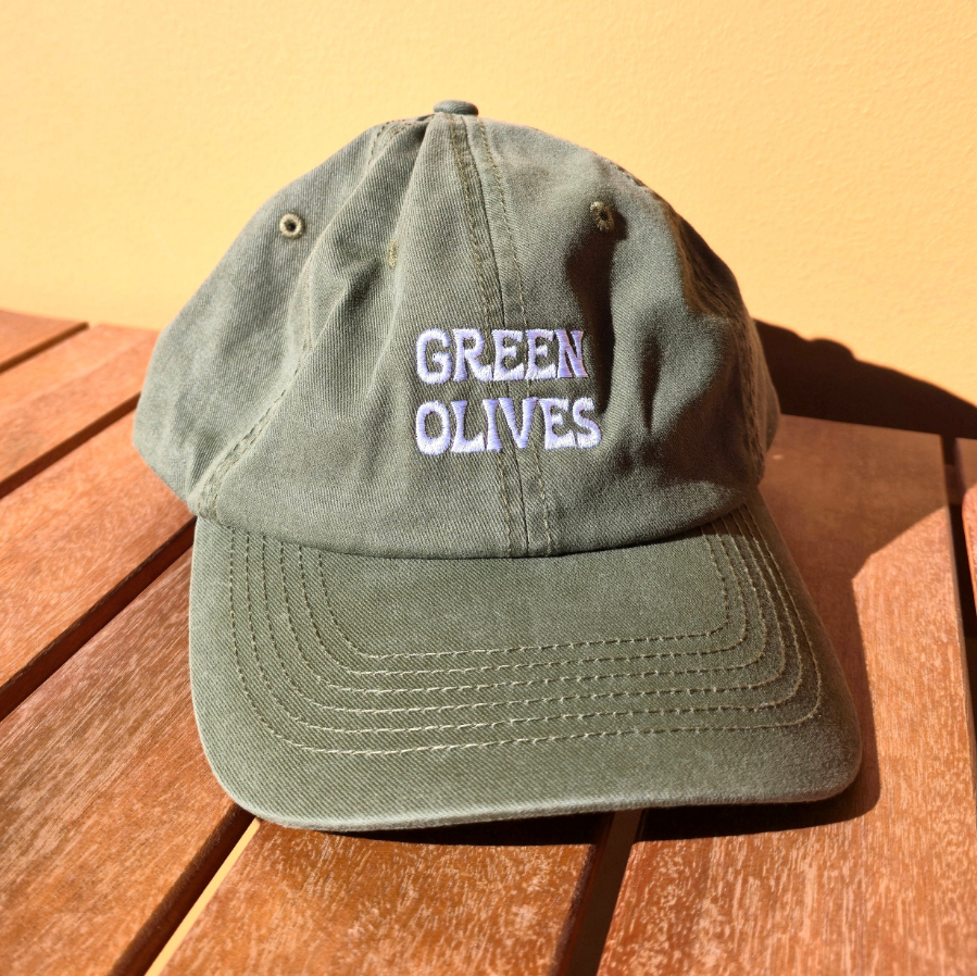 Green cap with 'GREEN OLIVES' text on a wooden surface