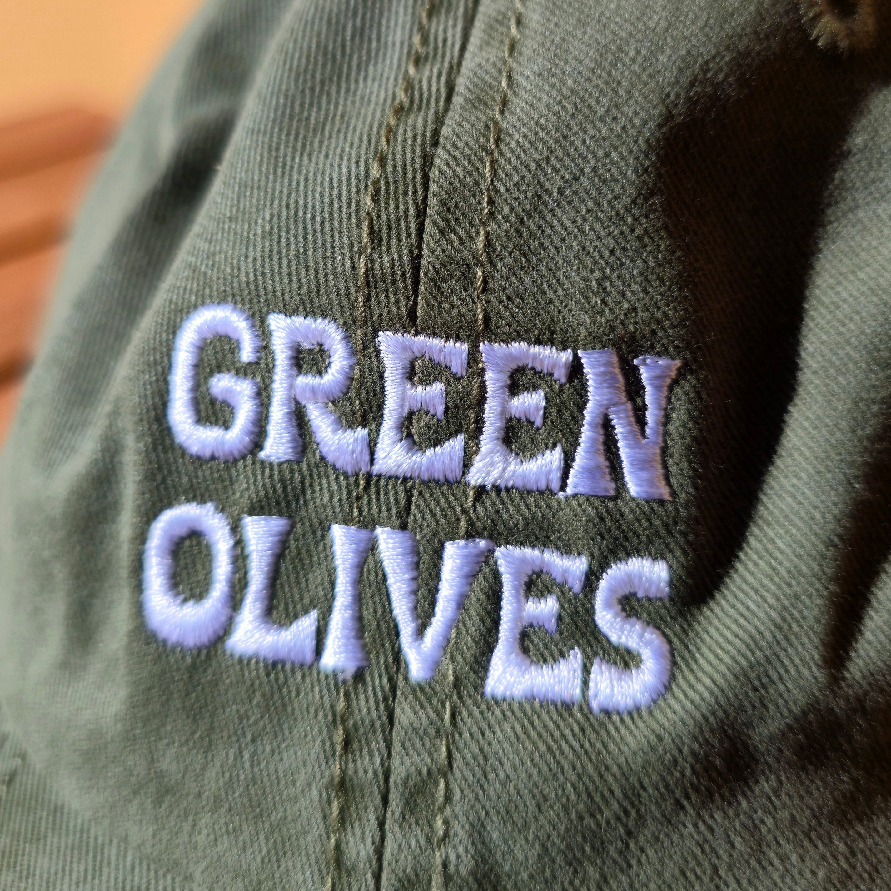 Green cap with 'GREEN OLIVES' embroidered on it against a beige background