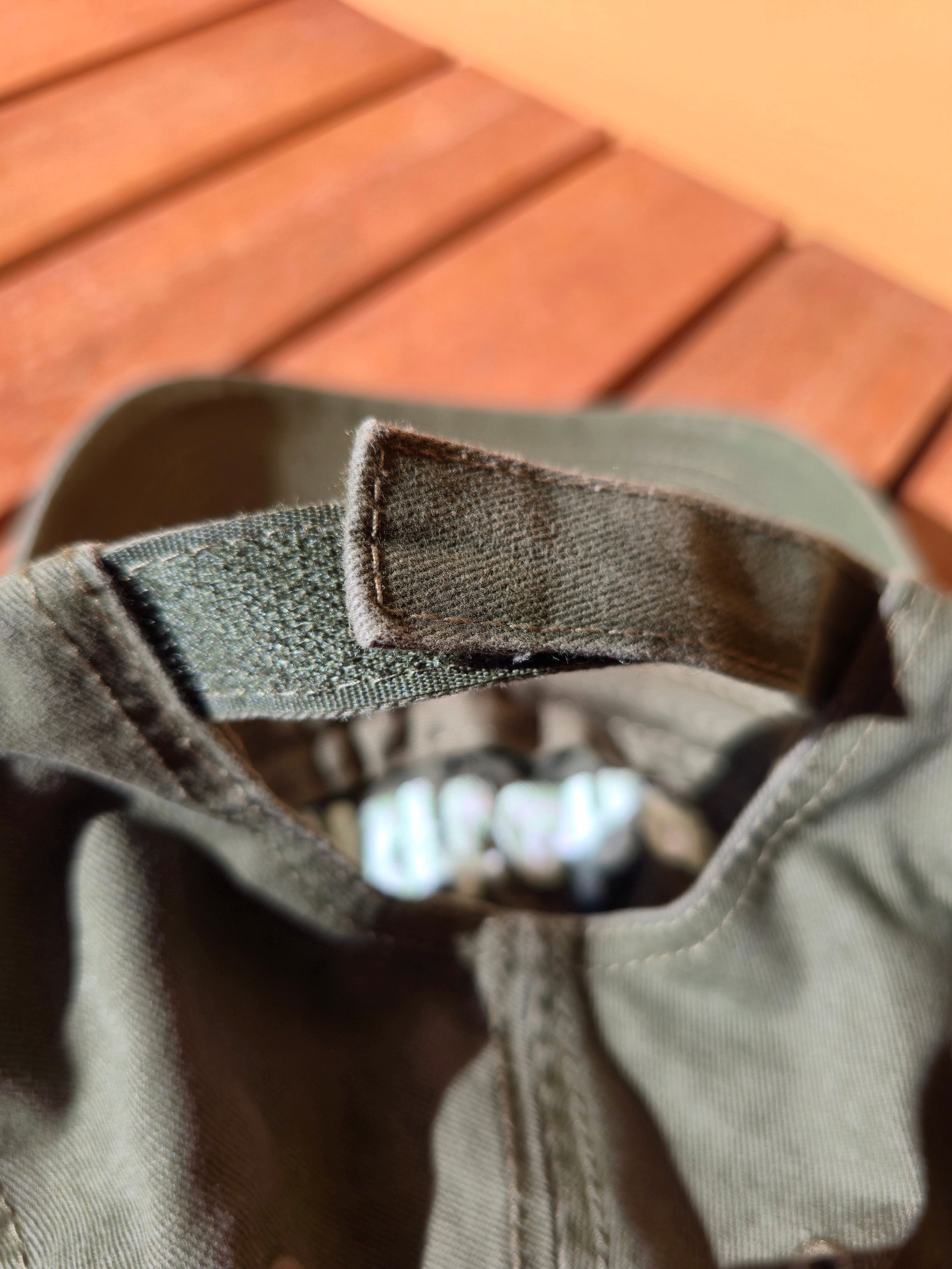 Close-up of a caps back with a strap on a wooden surface.