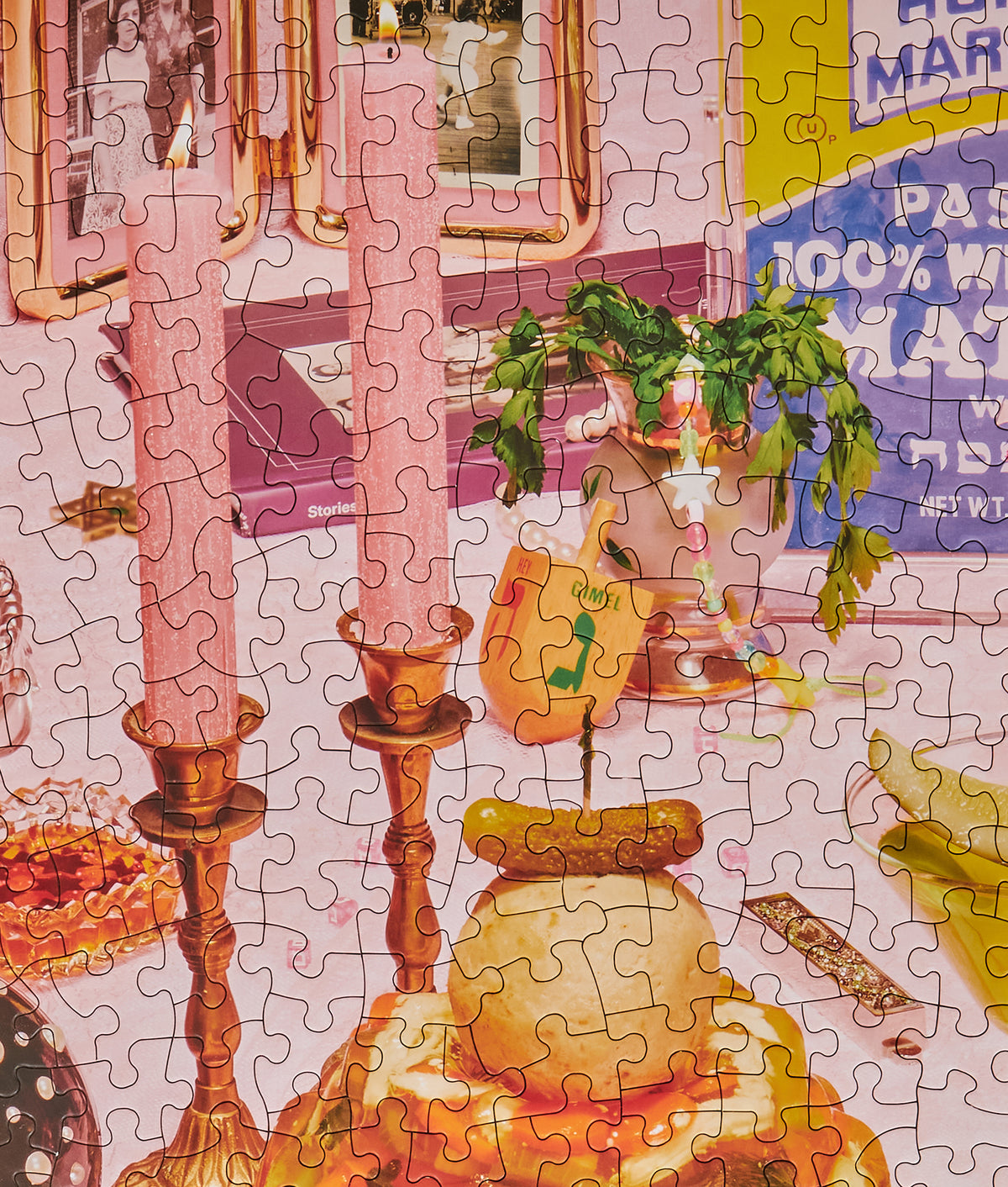 Close-up of the assembled Jewish American Puzzle showing pink candles, framed photos, a plant and a matzo box.