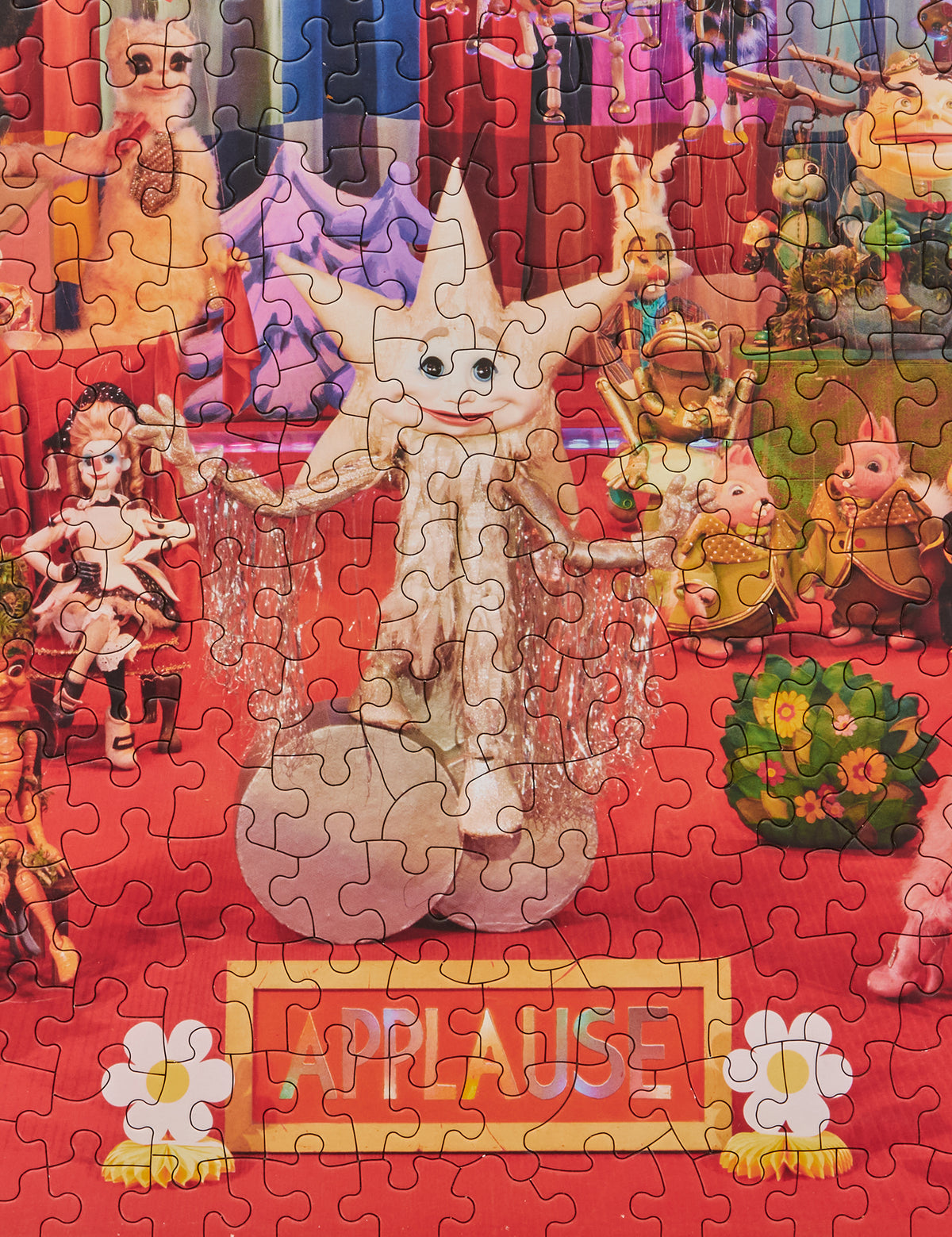 Close-up of the completed On a Heartstring puzzle showing a silver star puppet and an “Applause” sign.