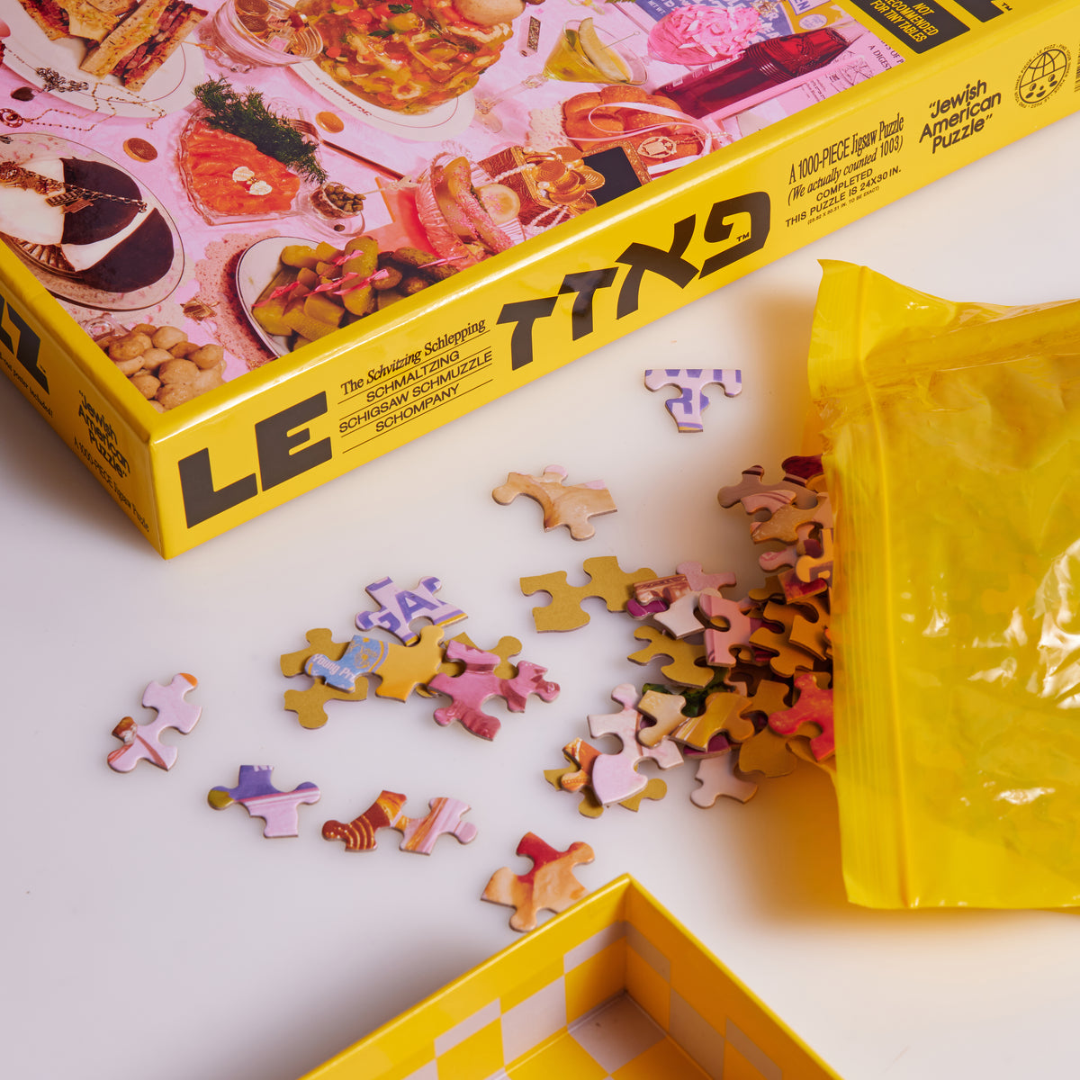 Jewish American Puzzle box beside loose jigsaw pieces spilling from a yellow bag.