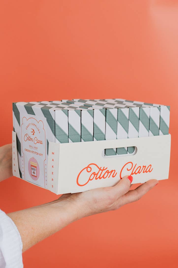 Cotton Clara product packaging held in a hand against an orange background