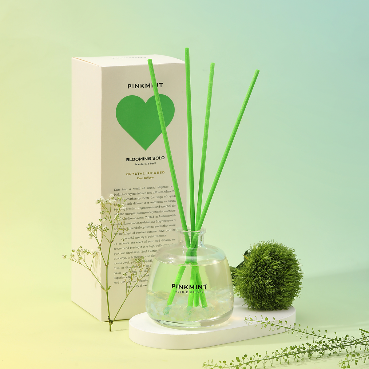 Pinkmint diffuser with green reeds and packaging on a light green background