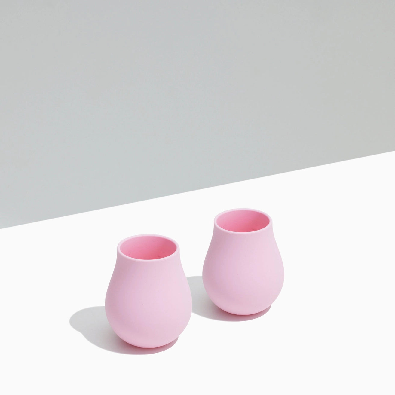 Two pink tumblers on a light gray and white background
