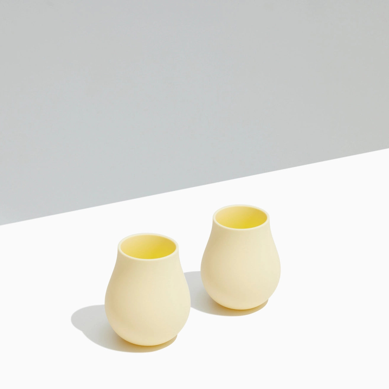 Two yellow silicone cups on a white surface with a light gray background