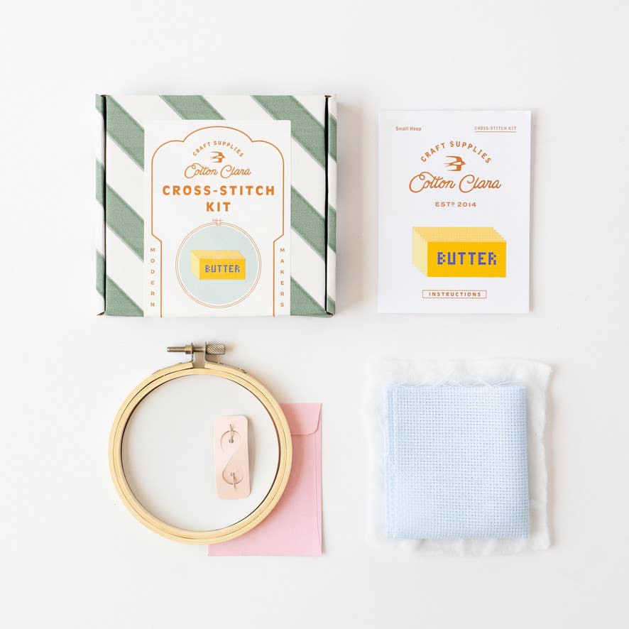 Cross-stitch kit with hoop, thread, and fabric on a white background