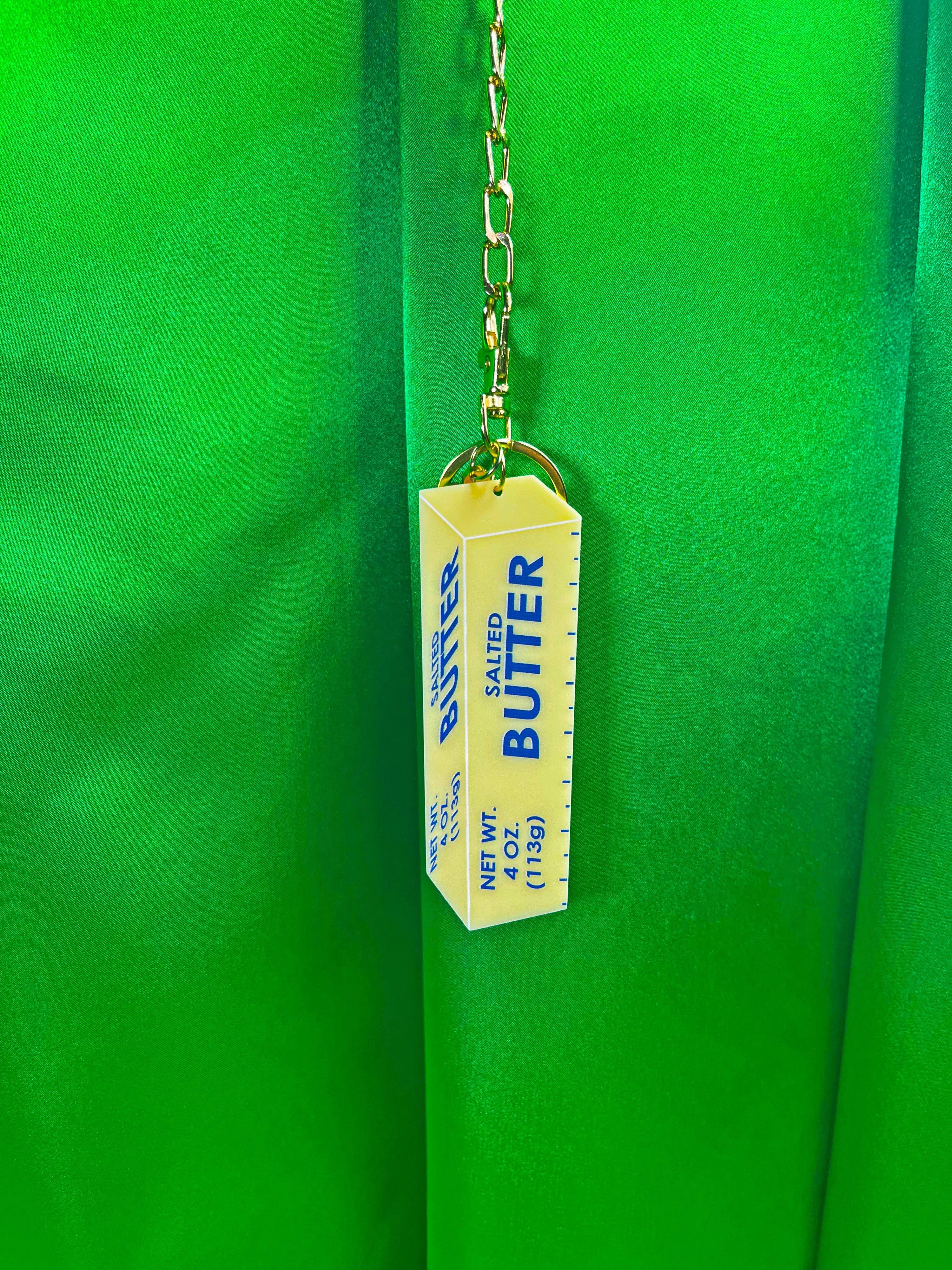 Butter Keychain hanging with green background