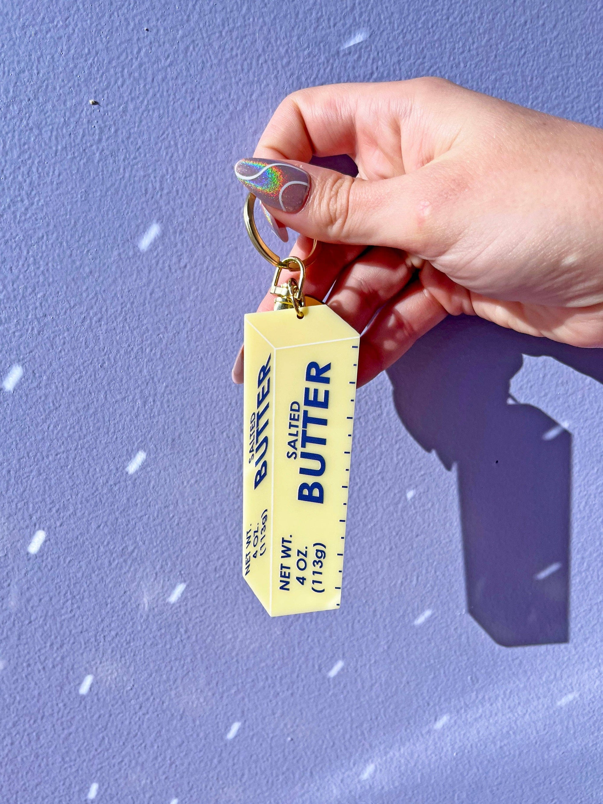 Butter Keychain held with hand and purple background