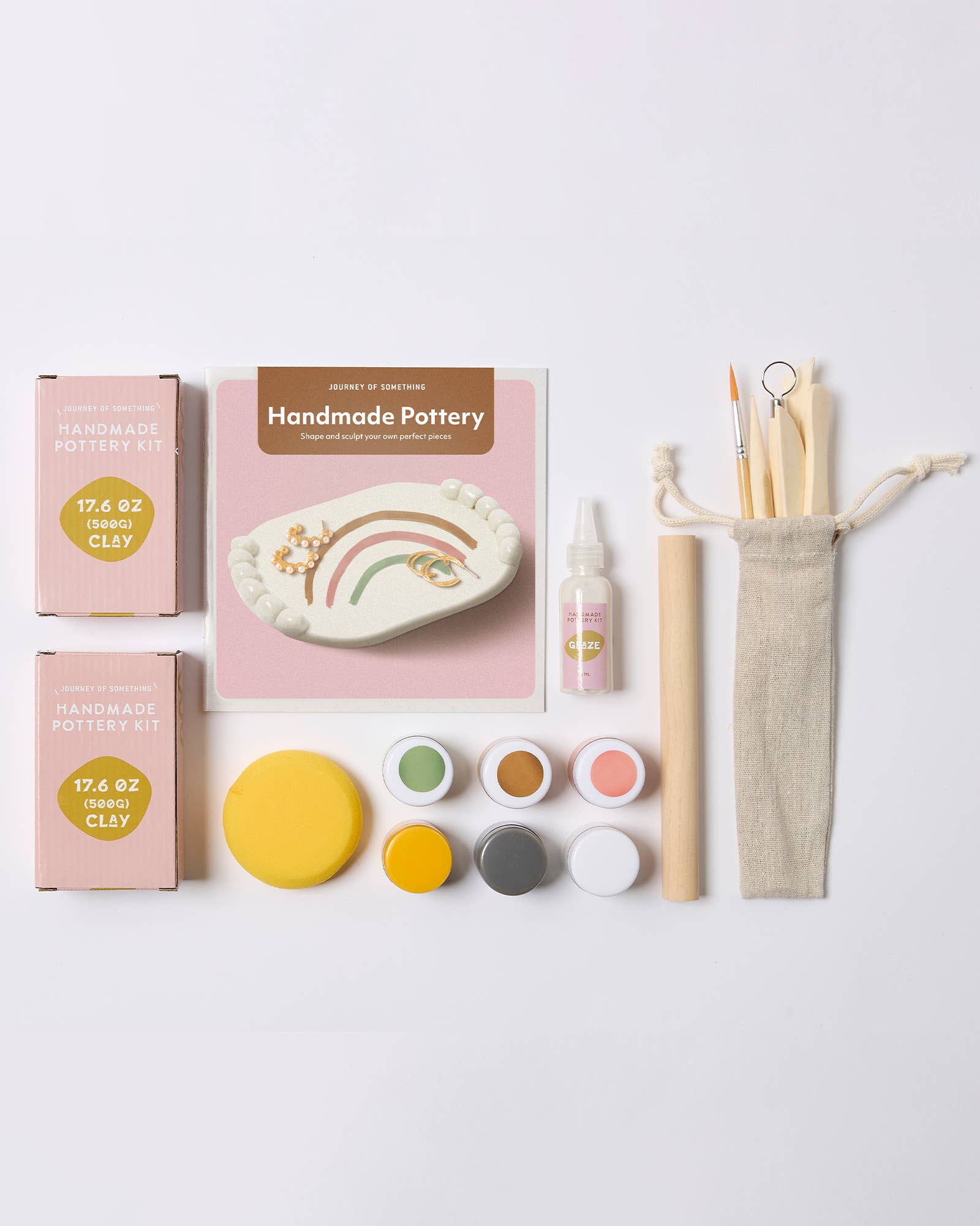 Handmade pottery kit with clay, tools, and packaging on a white background