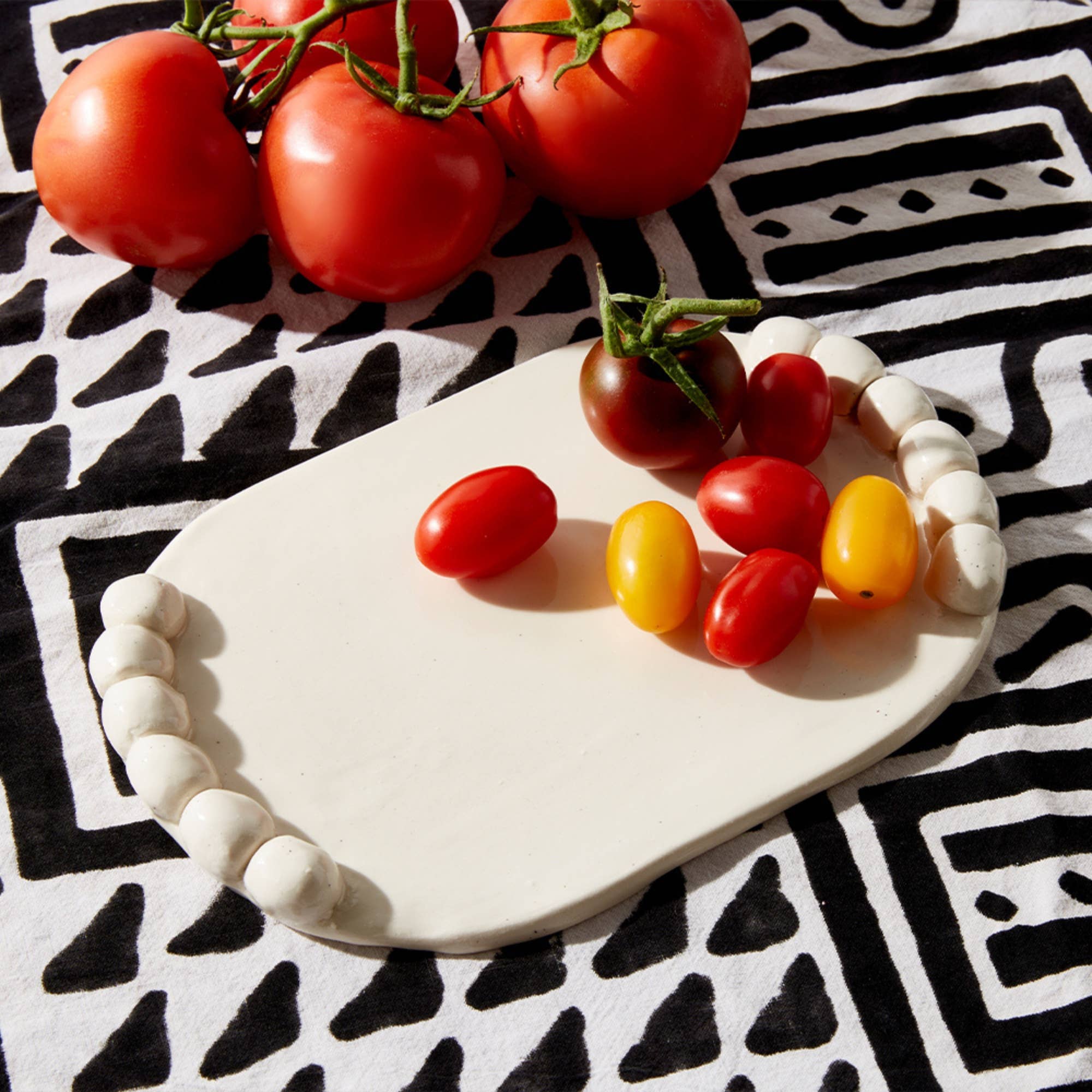 Tomatoes on a white ceramic plate with a black and white patterned background