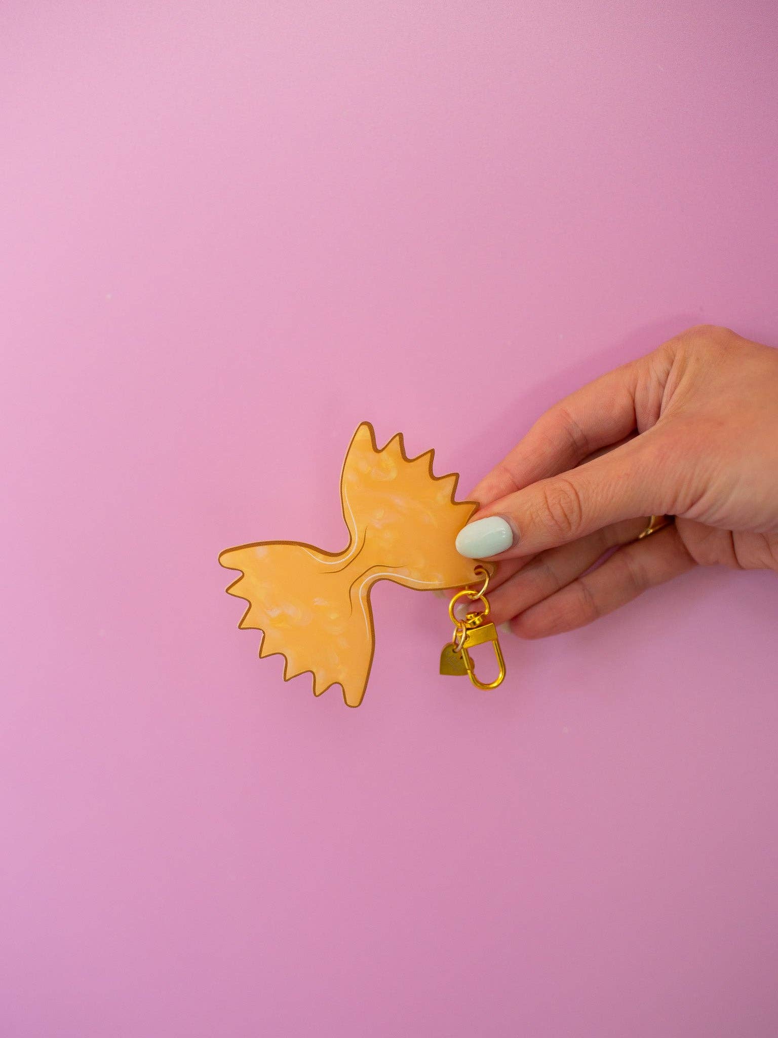 Farfalle Pasta Keychain with lavender background held by a hand 