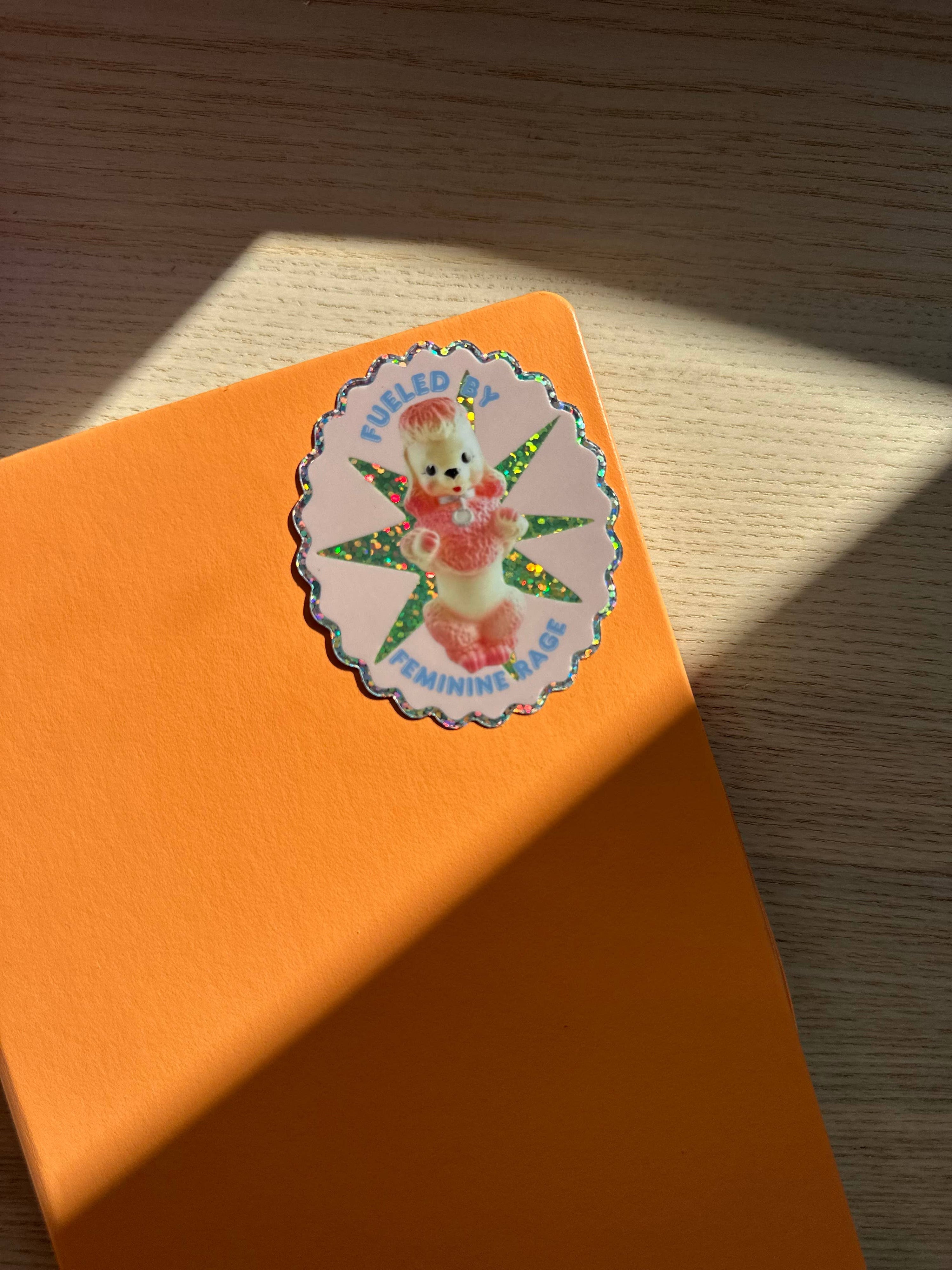 Orange notebook with a sticker featuring a cartoon character on a wooden surface