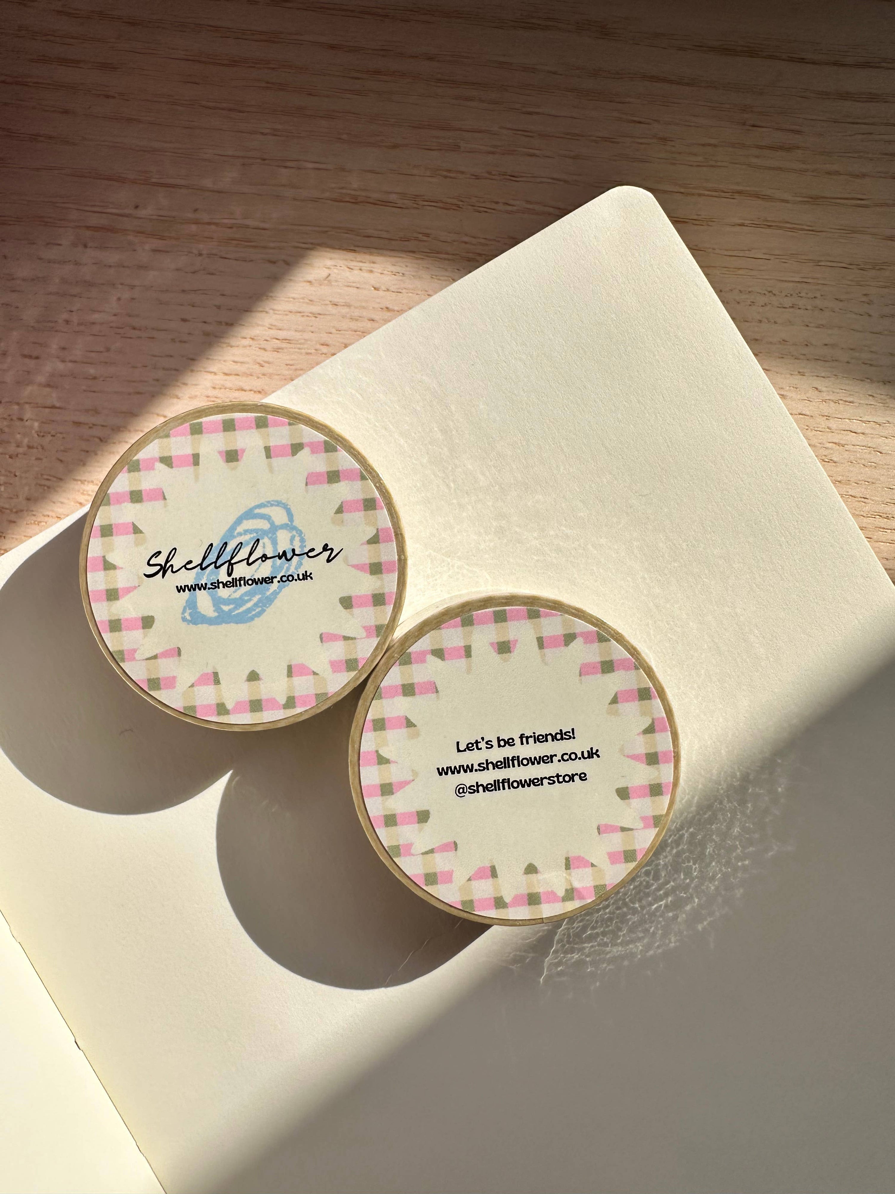 Two round stickers with a checkered border on a beige surface.