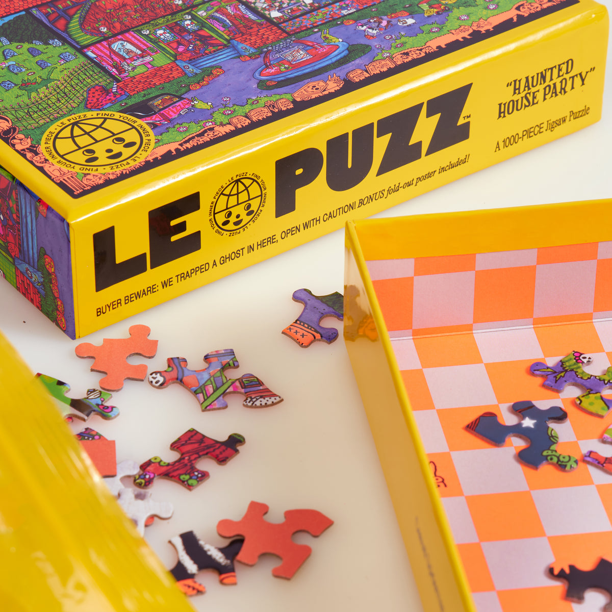 Close-up of the Haunted House Party puzzle box, loose pieces and orange-and-pink checked box interior.
