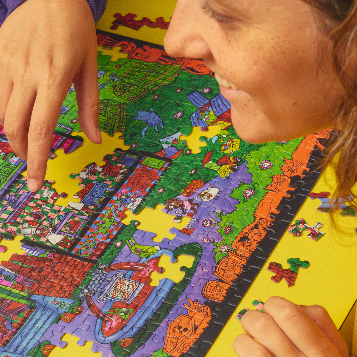 Close-up of a smiling person pointing at the partially assembled Haunted House Party puzzle.