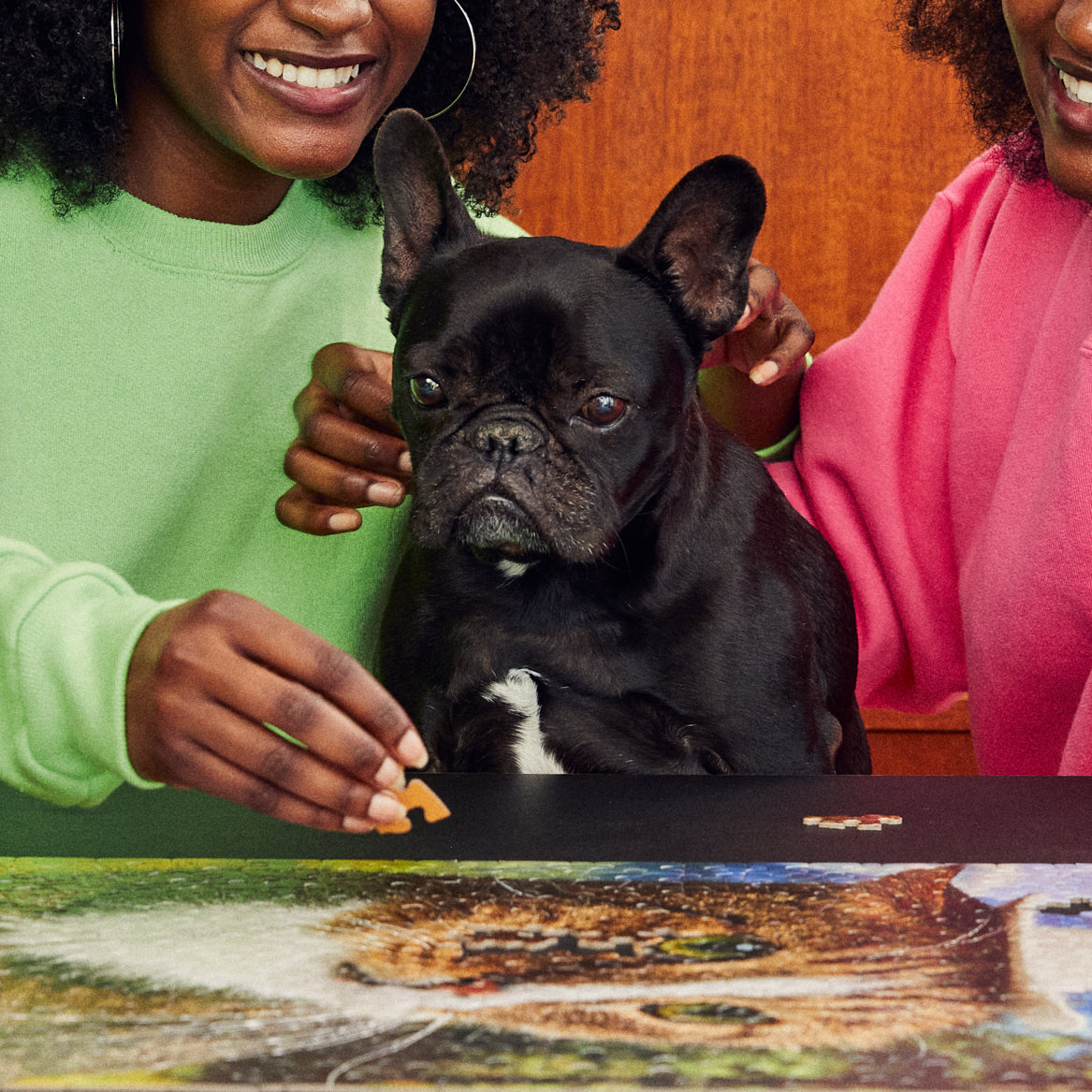 Two women with a french bulldog putting together the howdy partner le puzz puzzle