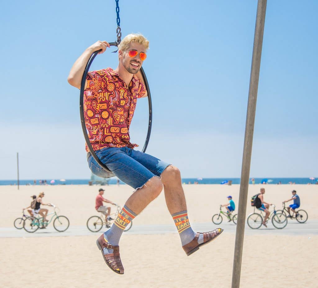 Person on a swing at the beach with people riding bicycles in the background