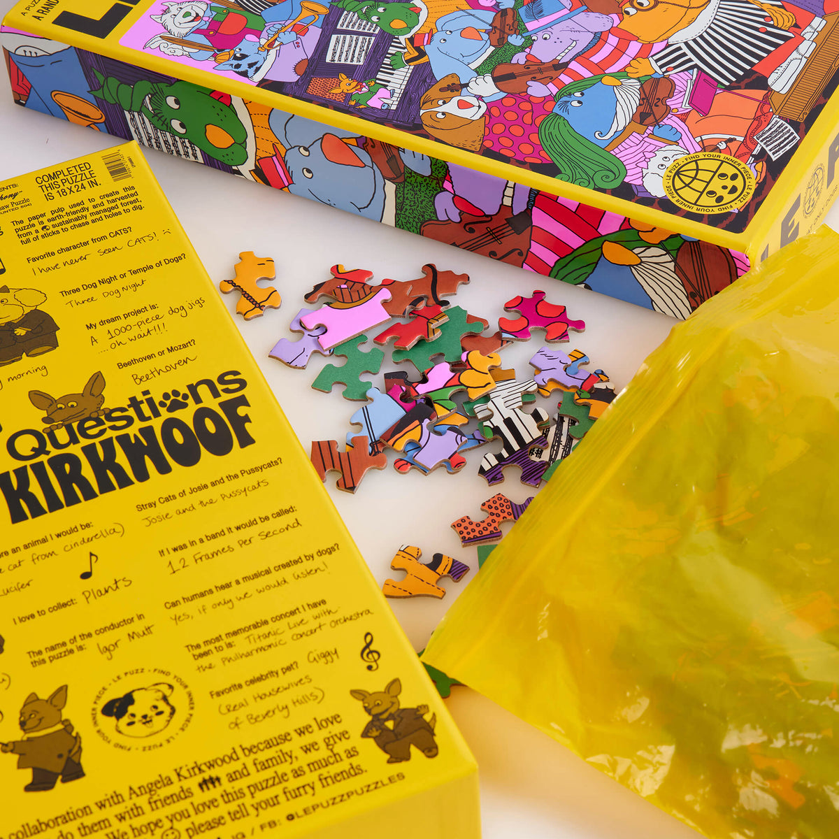Le Puzz K9 Symphony puzzle packaging with colourful loose pieces, a yellow storage bag and Angela Kirkwood interview text