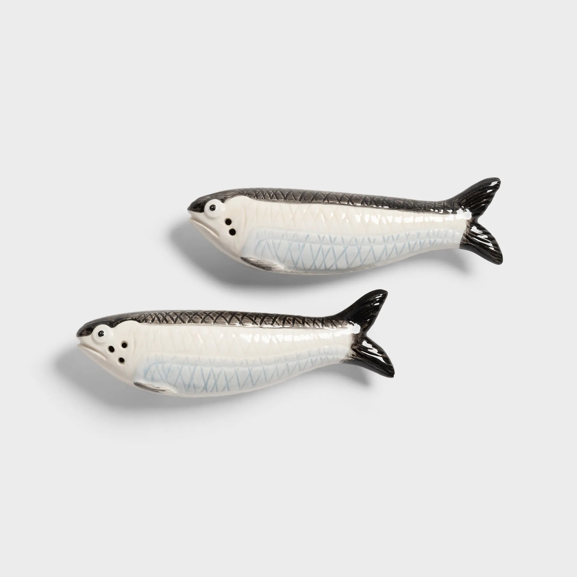 Two ceramic sardine fish-shaped salt and pepper shakers on a light gray background