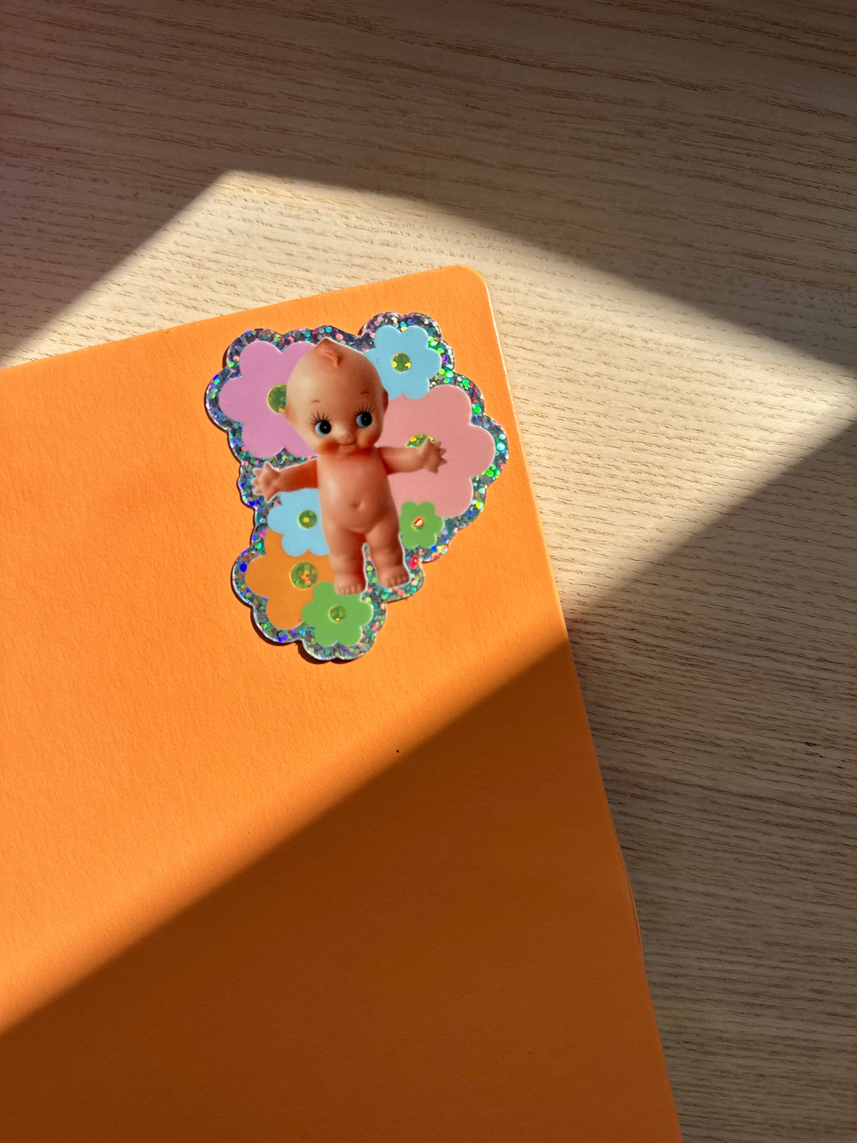 Colorful sticker of a baby on an orange surface with wooden background