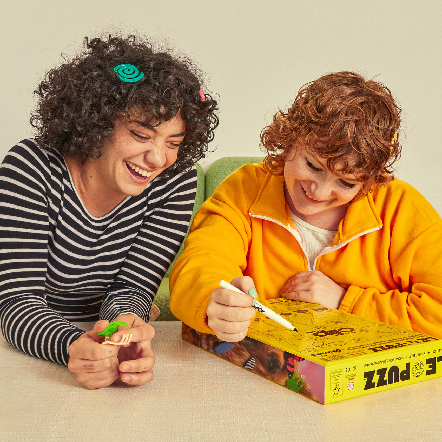 Two people playing with a board game box on a light background