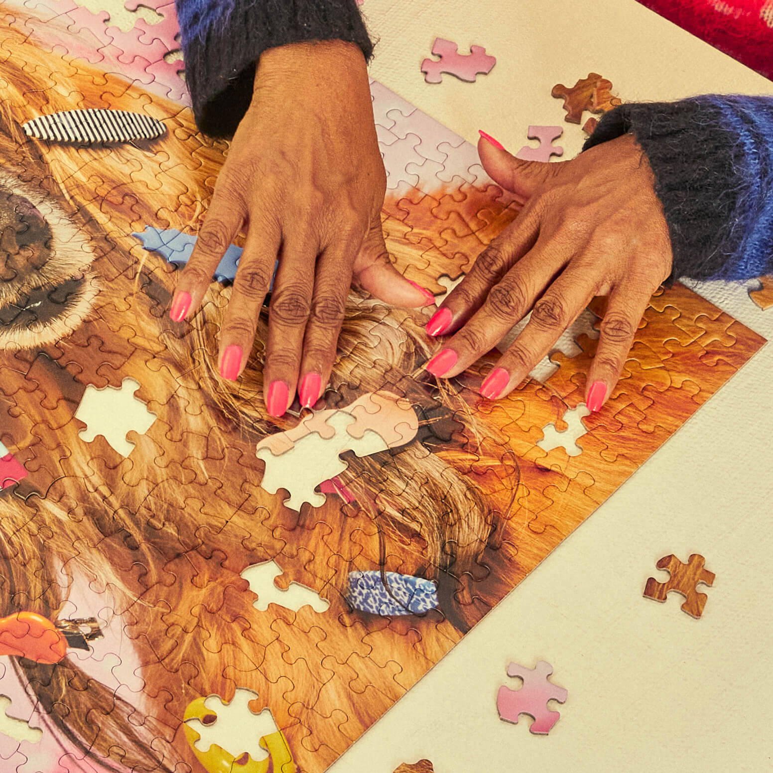 Person assembling a puzzle with a focus on hands and puzzle pieces.