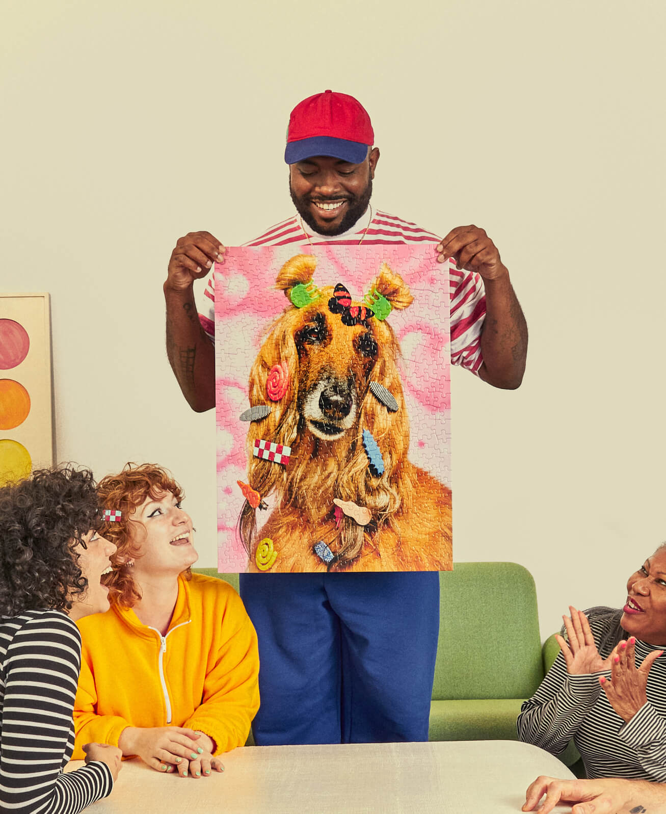 Person holding a jigsaw puzzle of a dog with decorative accessories, surrounded by four people in a casual setting.