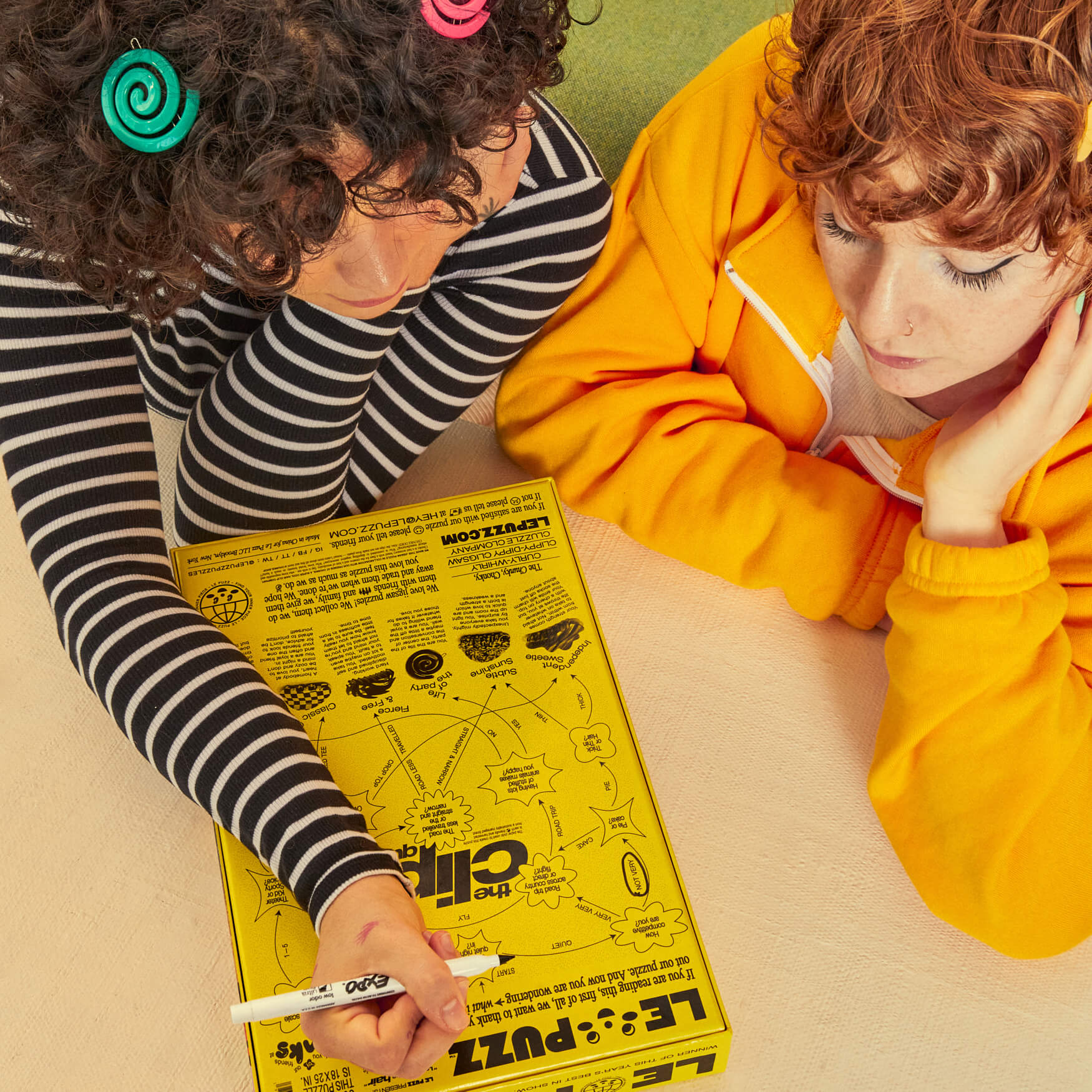 Two children looking at a yellow puzzle box on a table.