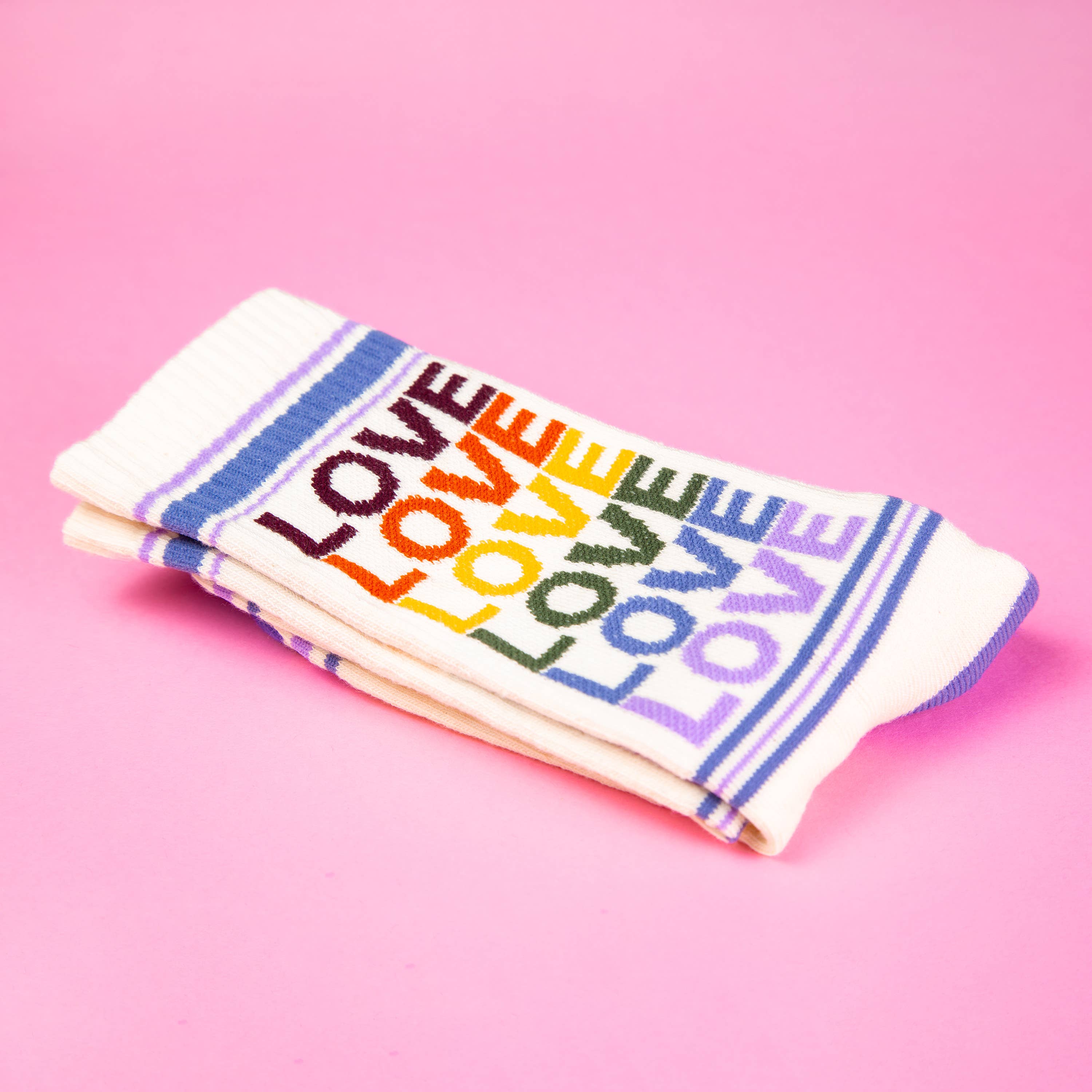 Folded socks  with 'LOVE' in rainbow colors on a pink background