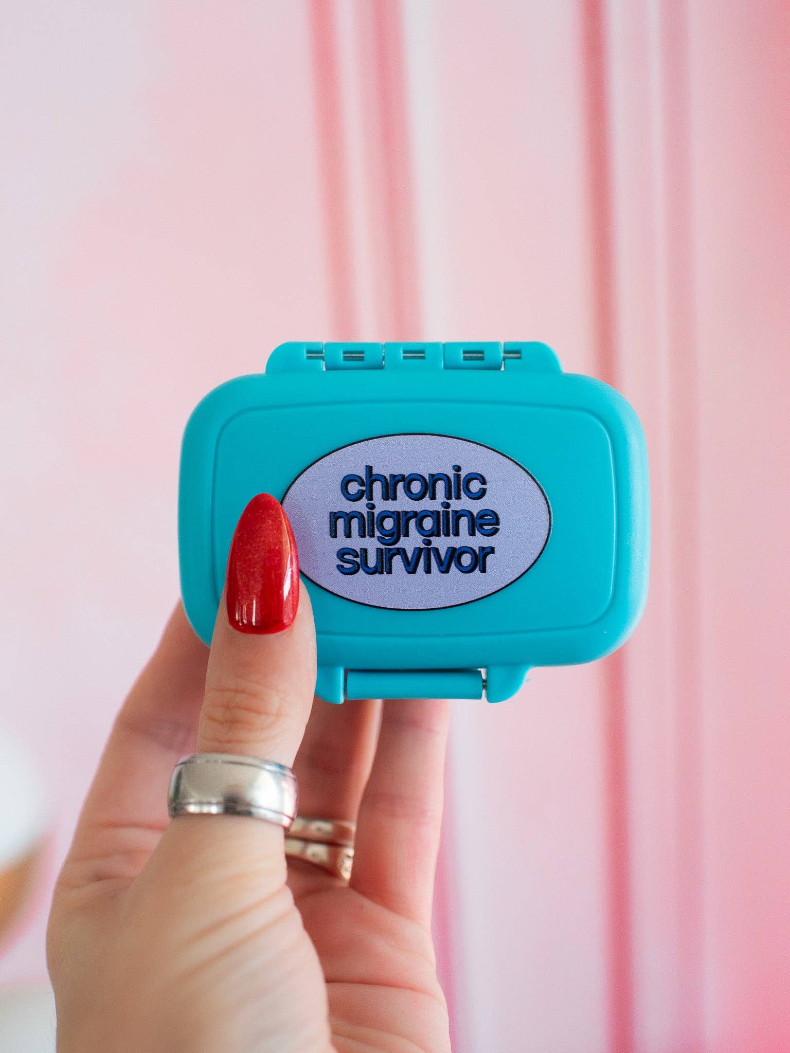 Blue case with 'chronic migraine survivor' text held by a hand against a pink background