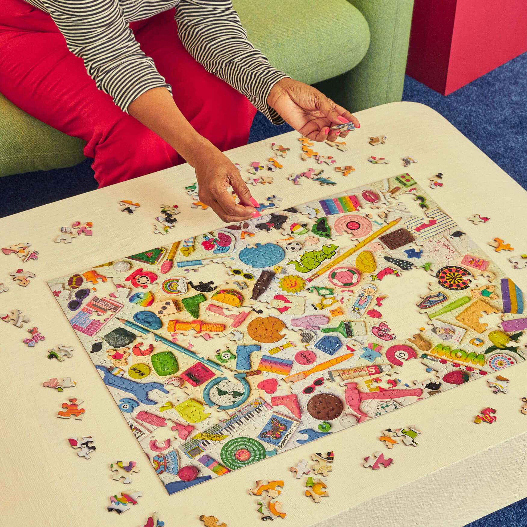 Person working on a colorful puzzle with various pieces on a table.