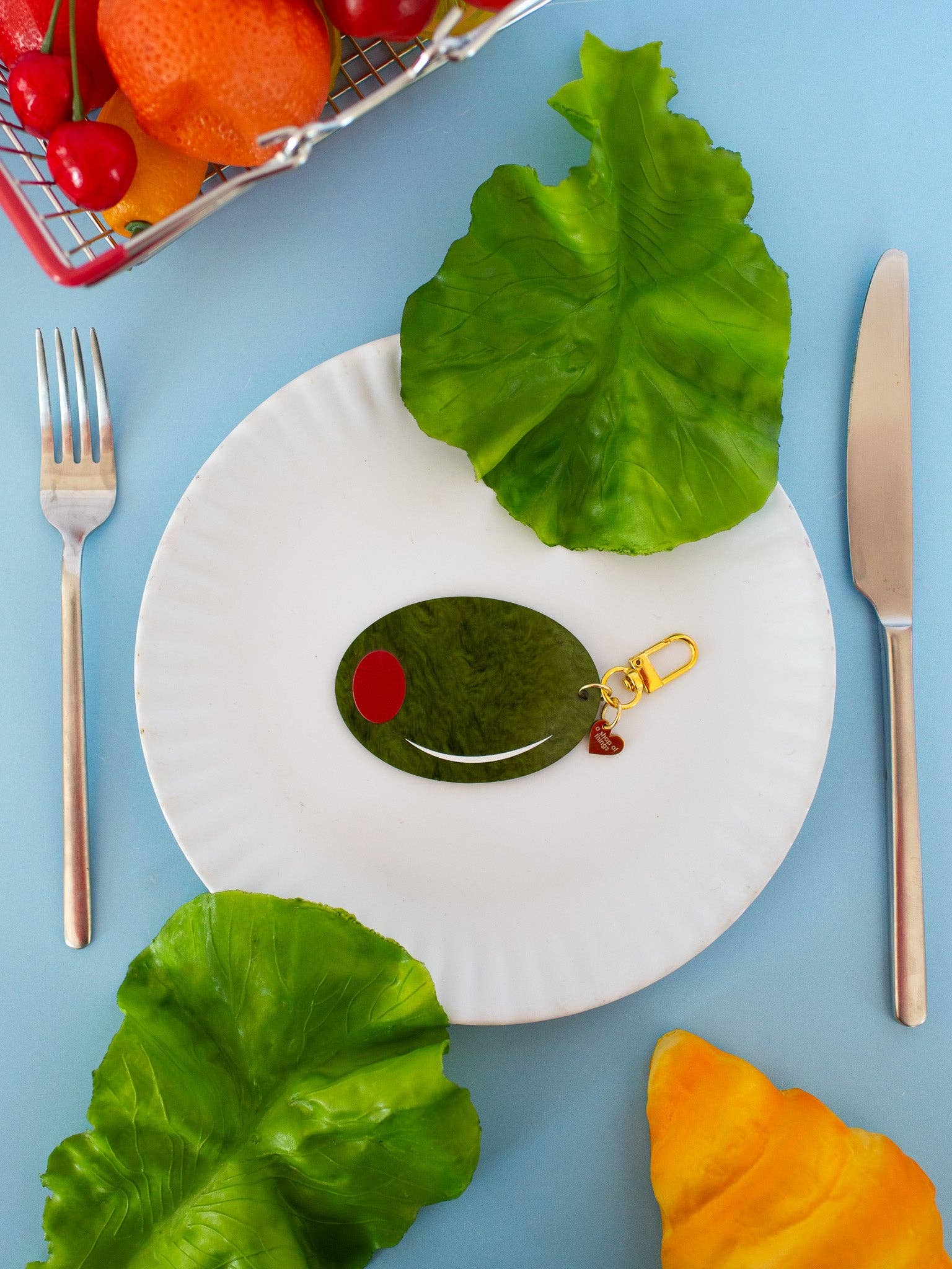 Olive Keychain on white plate with blue table 