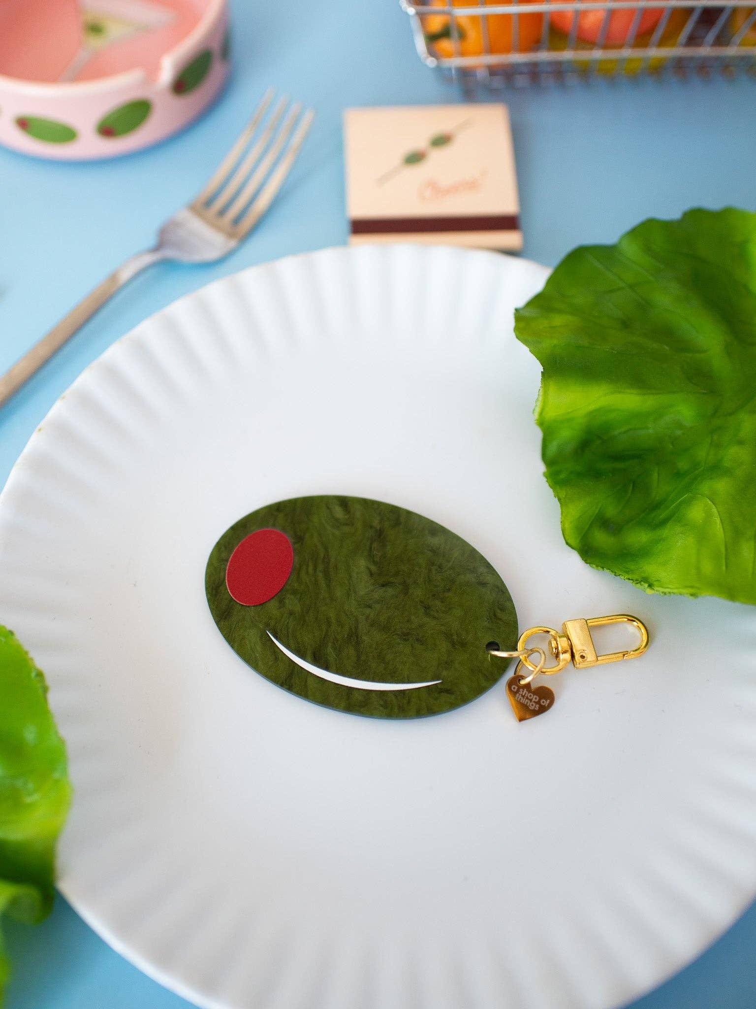 Olive Keychain close up on white plate with blue table cloth