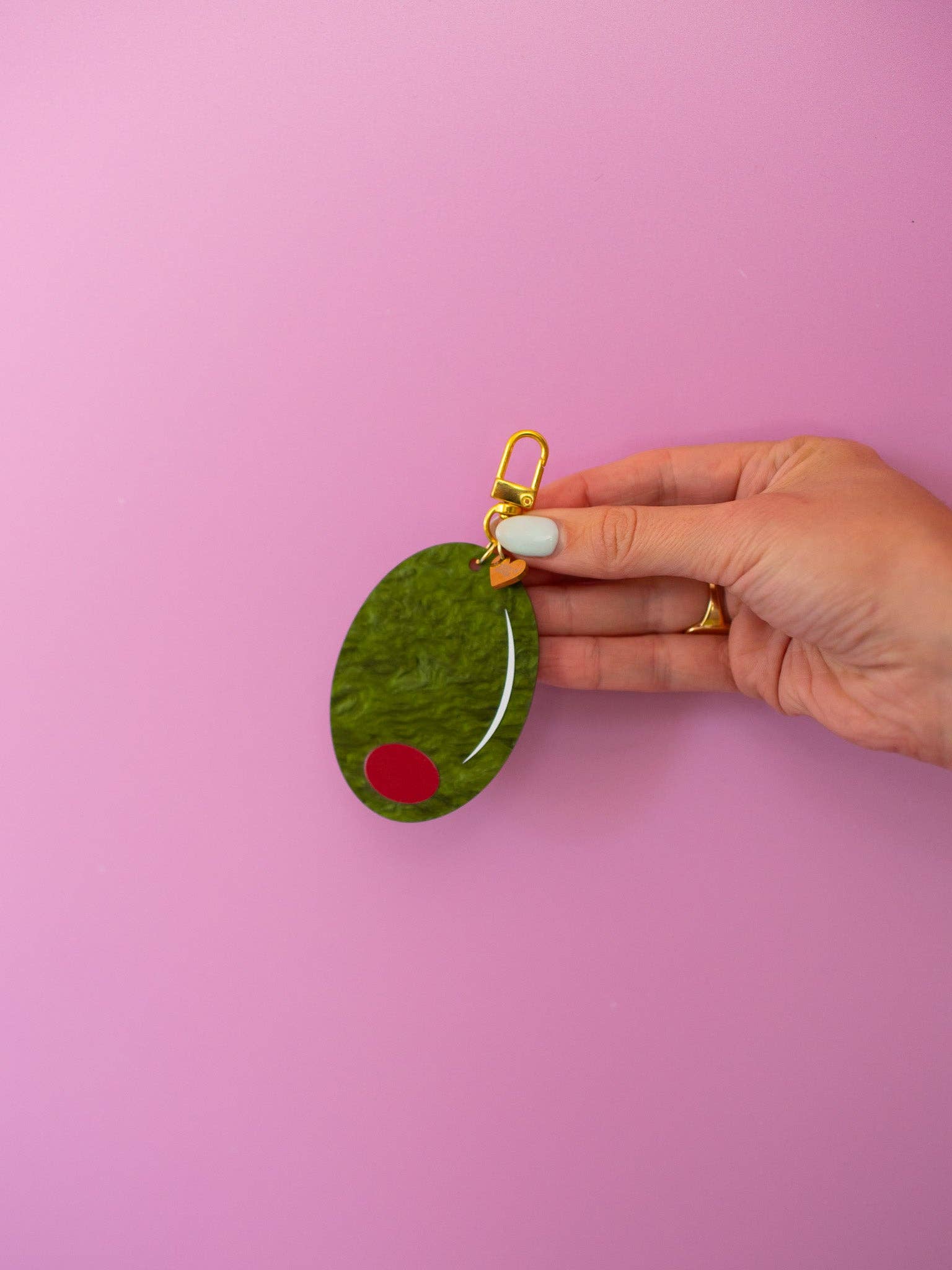 Olive Keychain with hand and purple ackground 
