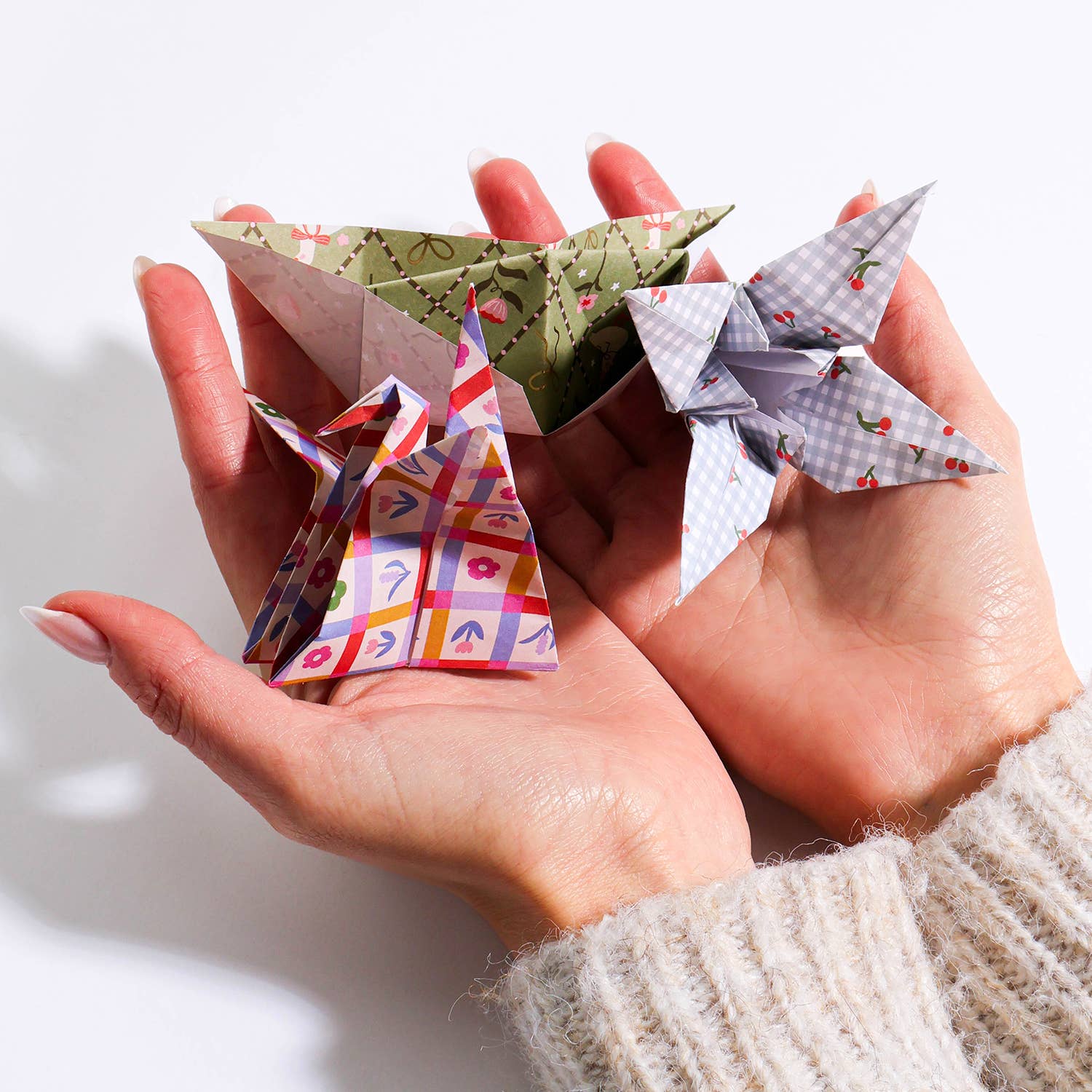 Hands holding colorful origami stars on a white background