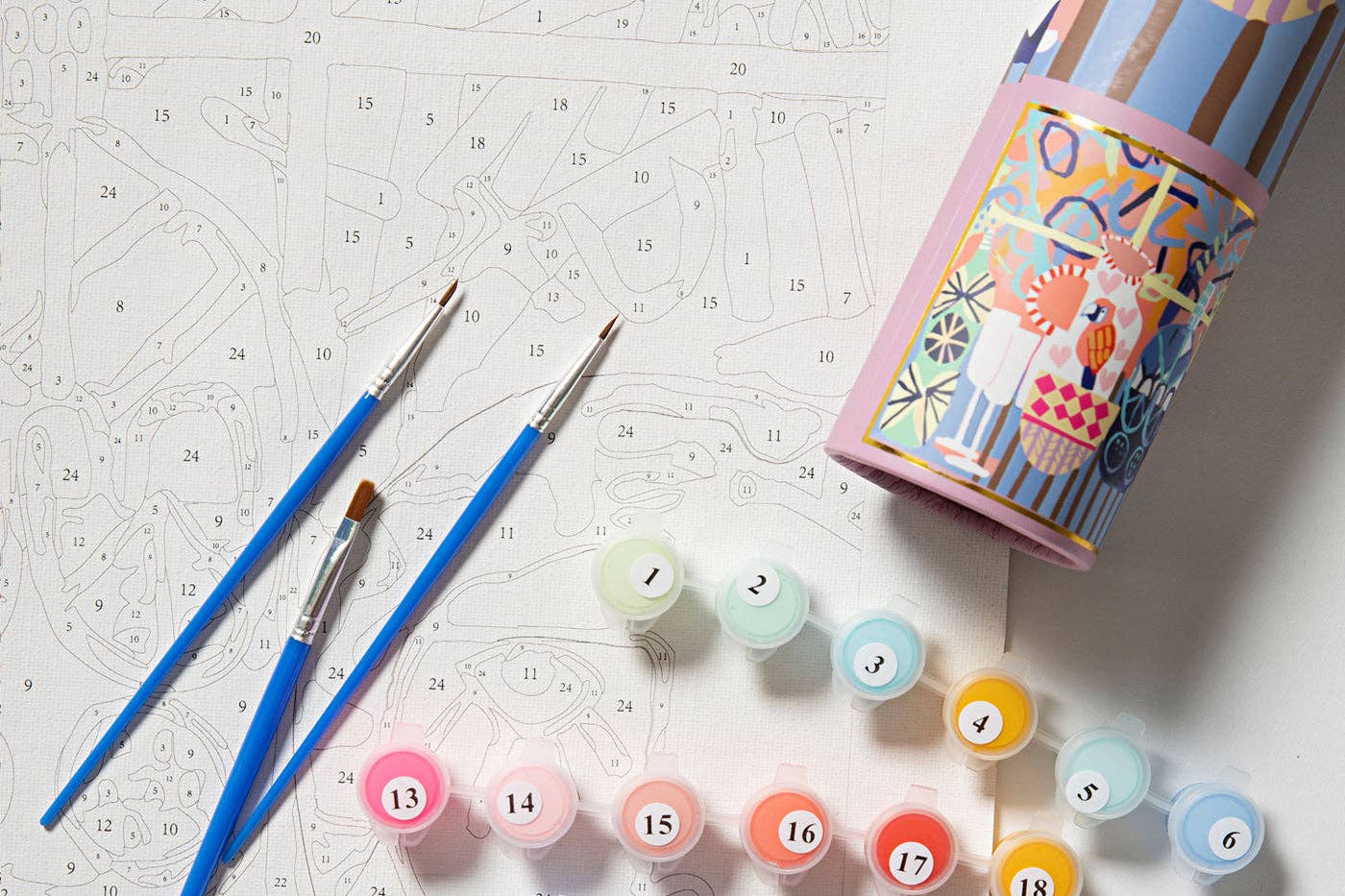 Colorful paint tubes with numbers and brushes on a patterned surface