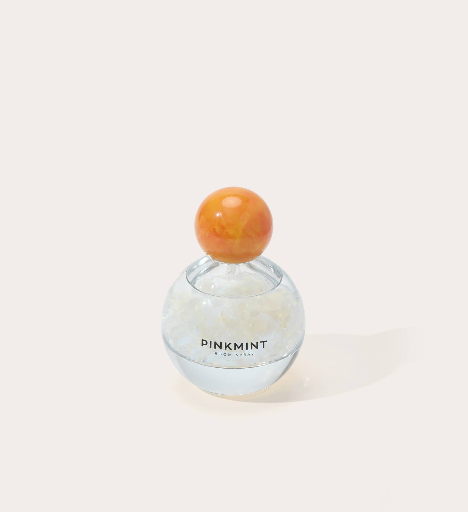 Perfume bottle with an orange cap on a light beige background
