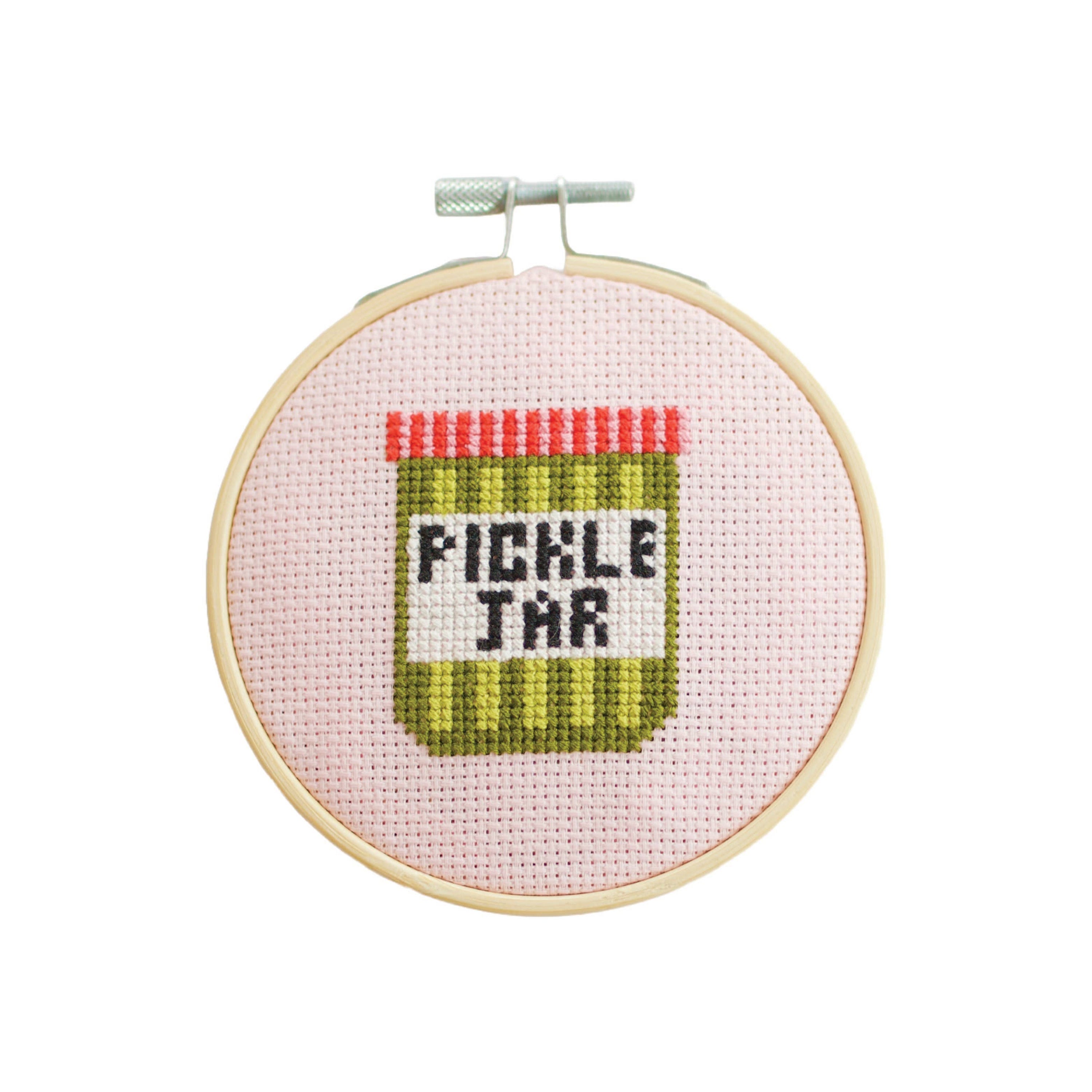 Embroidery hoop with a cross-stitched pickle jar design on pink fabric.