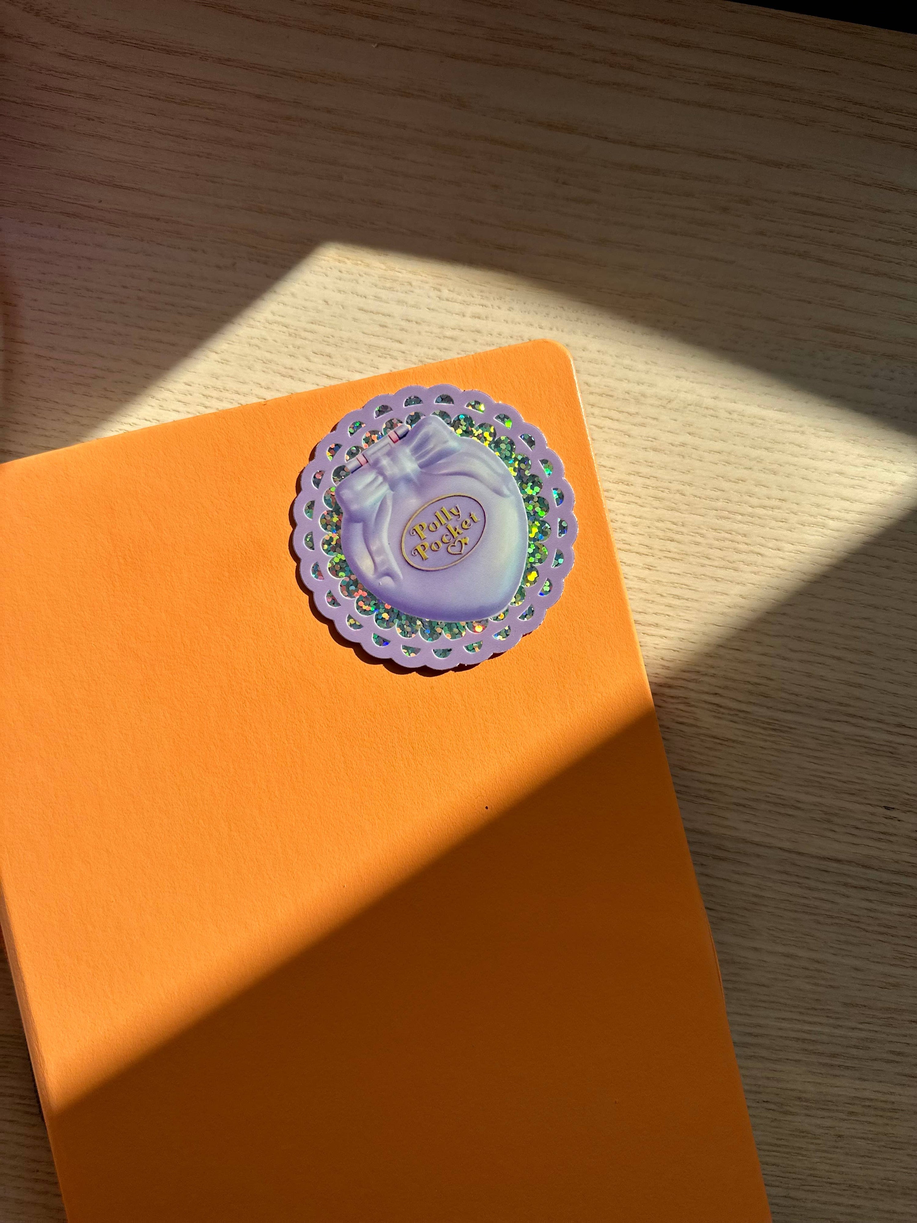 Orange box with a decorative label featuring a perfume bottle on a wooden surface.