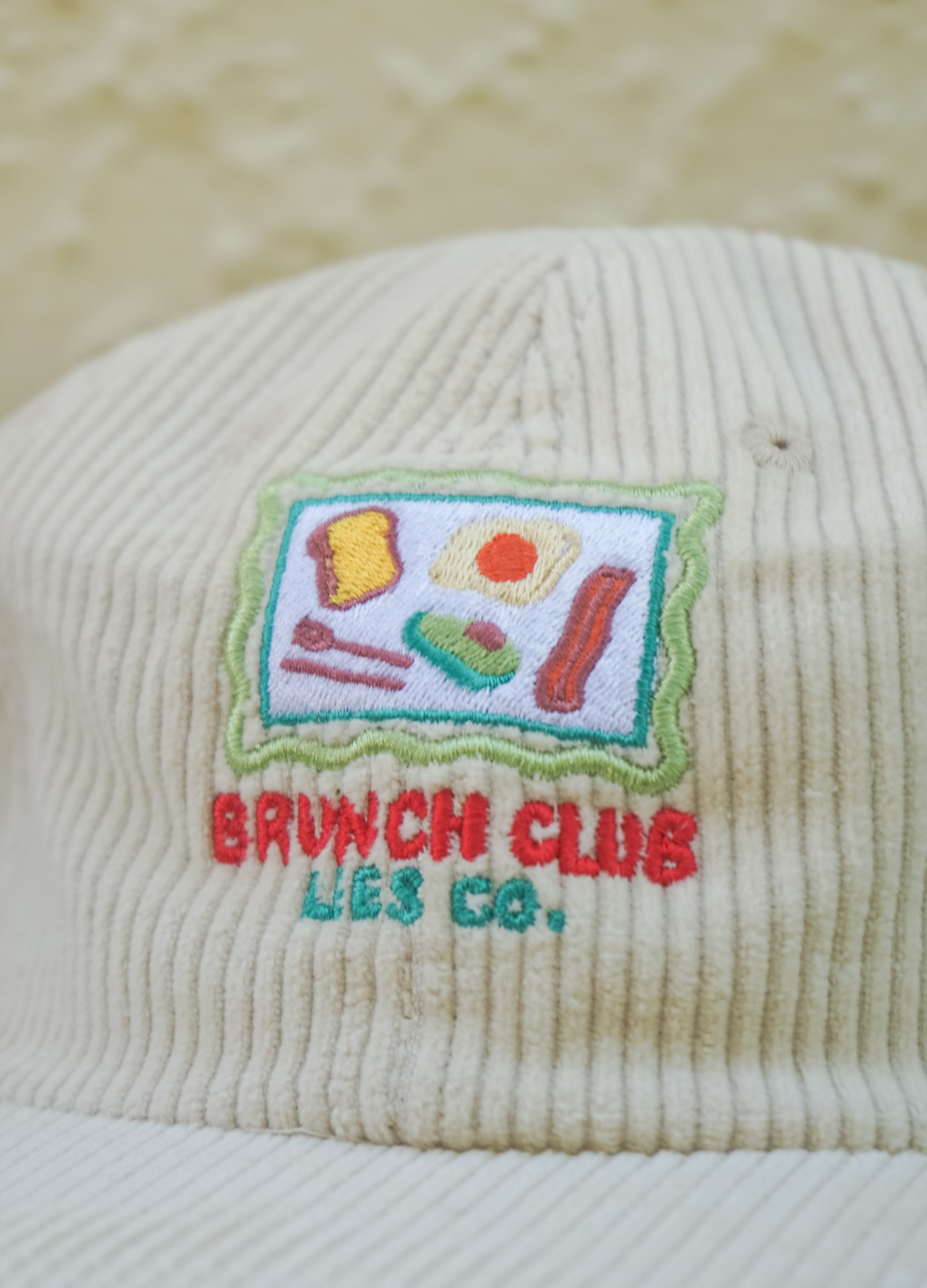 Beige corduroy cap with embroidered 'Brunch Club' design on a beige background