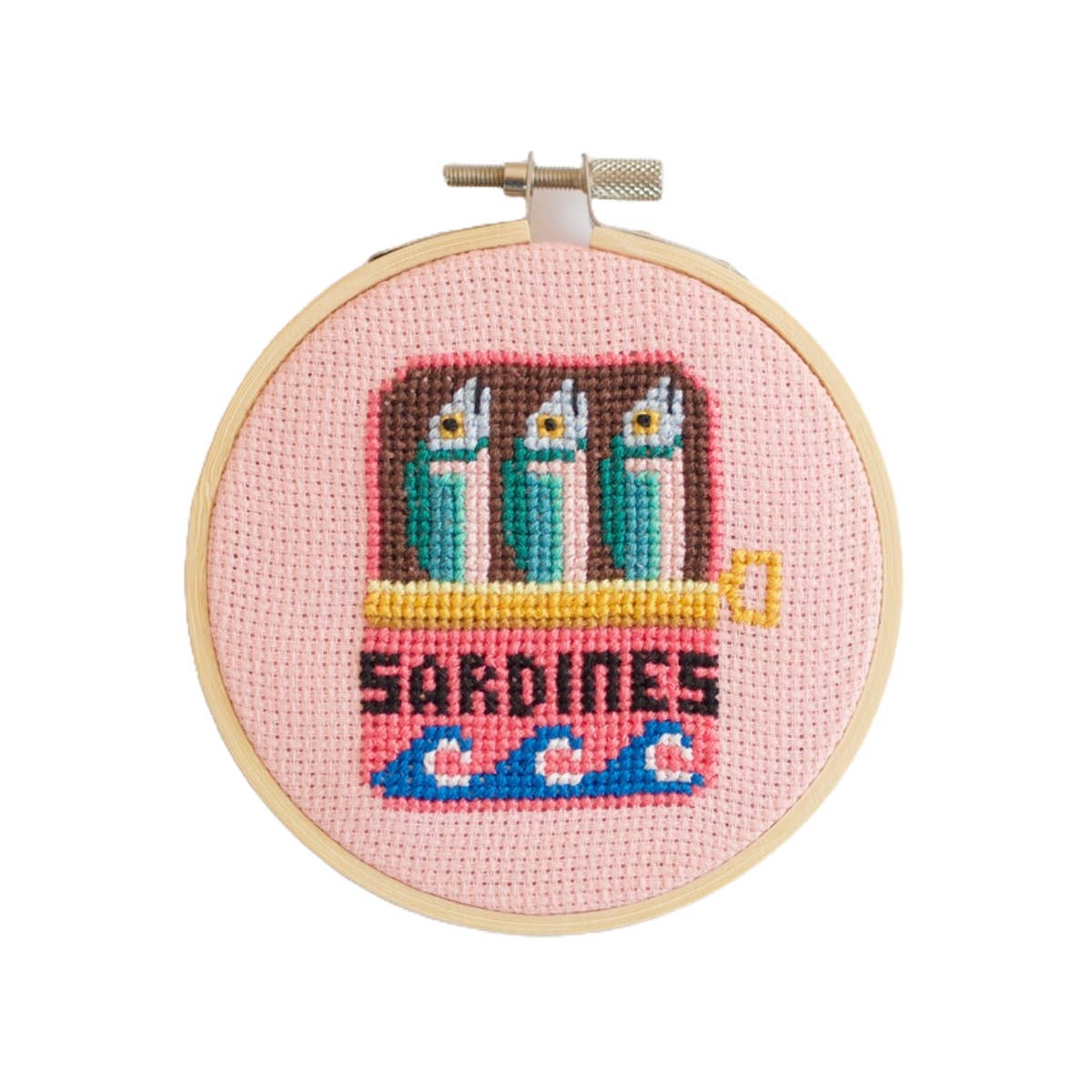 Cross-stitched design of sardines in a can on a pink background, framed in a wooden hoop.