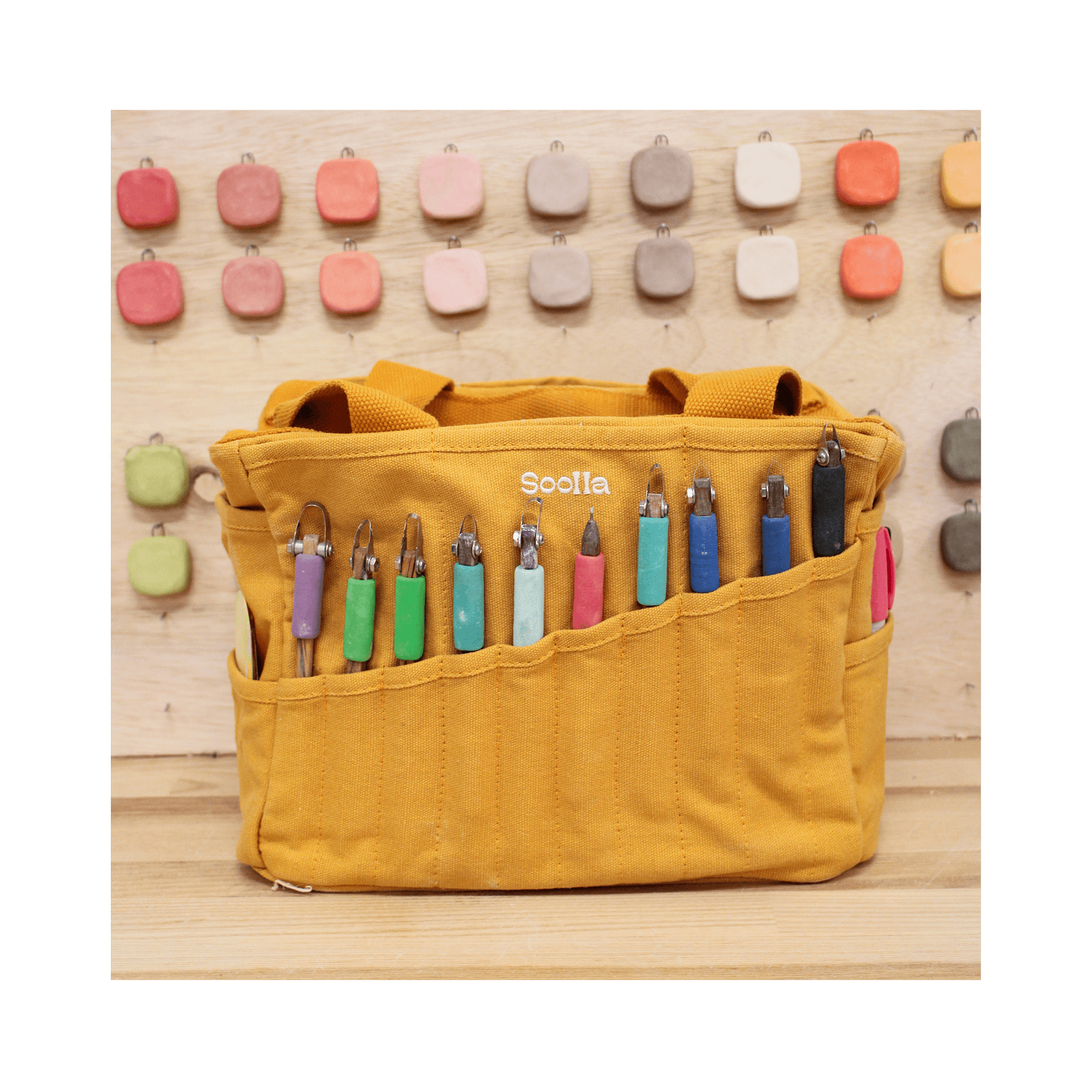 Yellow tool bag with colorful tools on a wooden surface and wall.