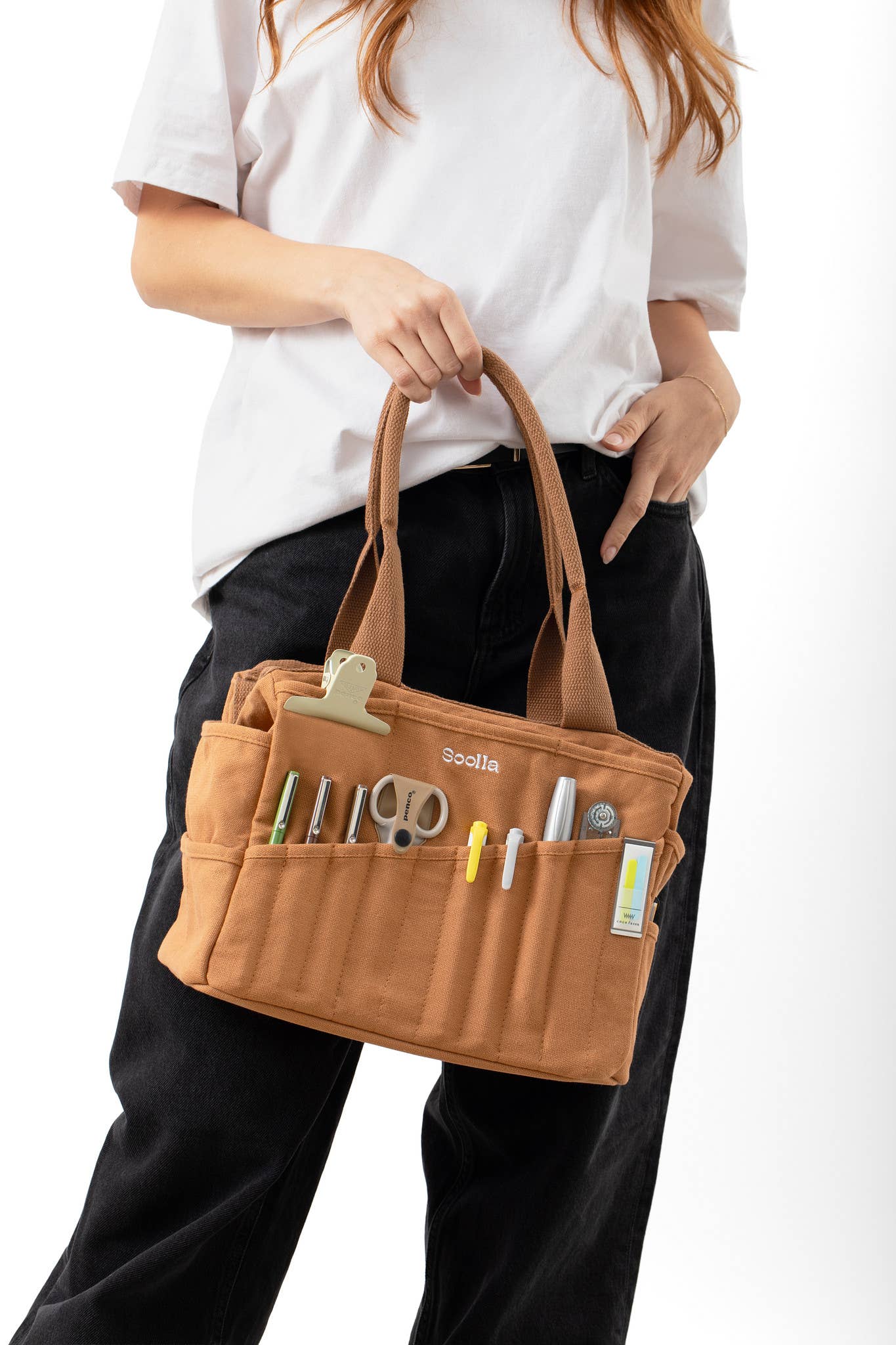 Person holding a brown tool bag with various tools on a white background