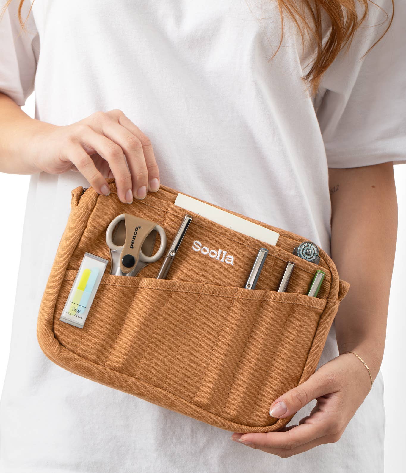 Person holding a brown tool pouch with various tools inside on a white background