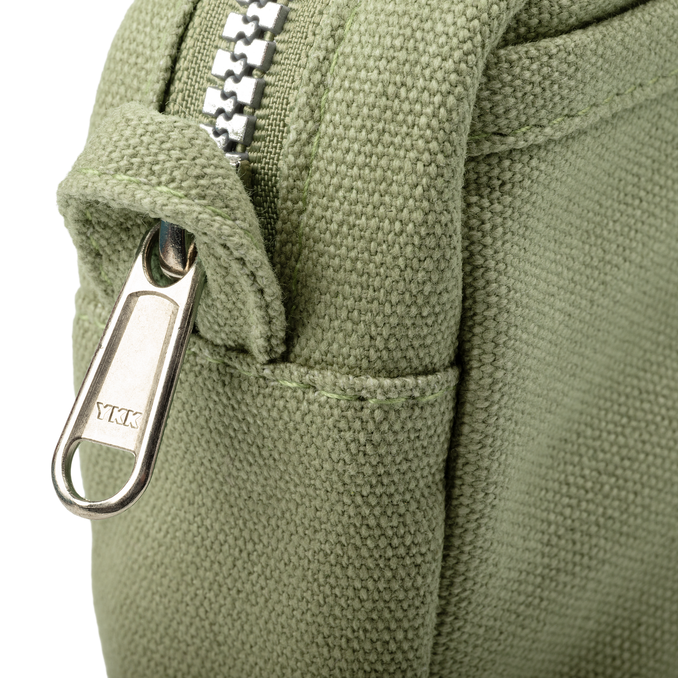 Close-up of a green fabric bag with a metal zipper and YKK branding.