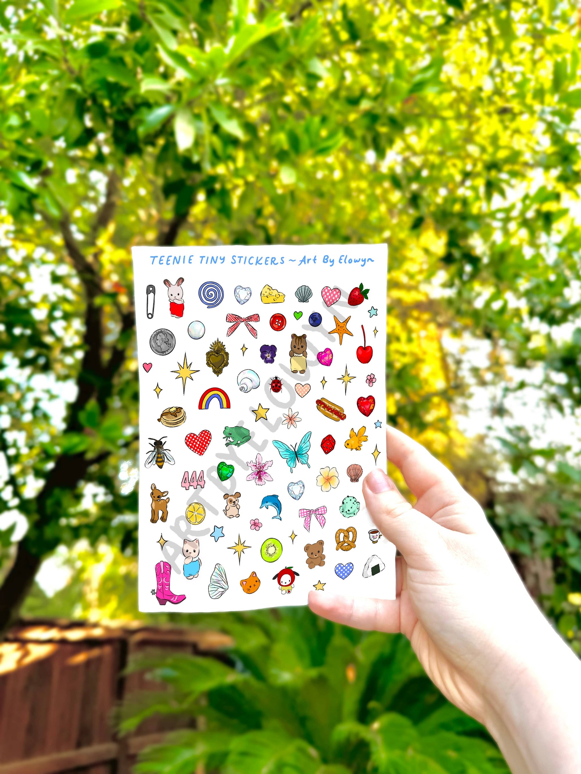 Sheet of colorful stickers held in front of a green, leafy background